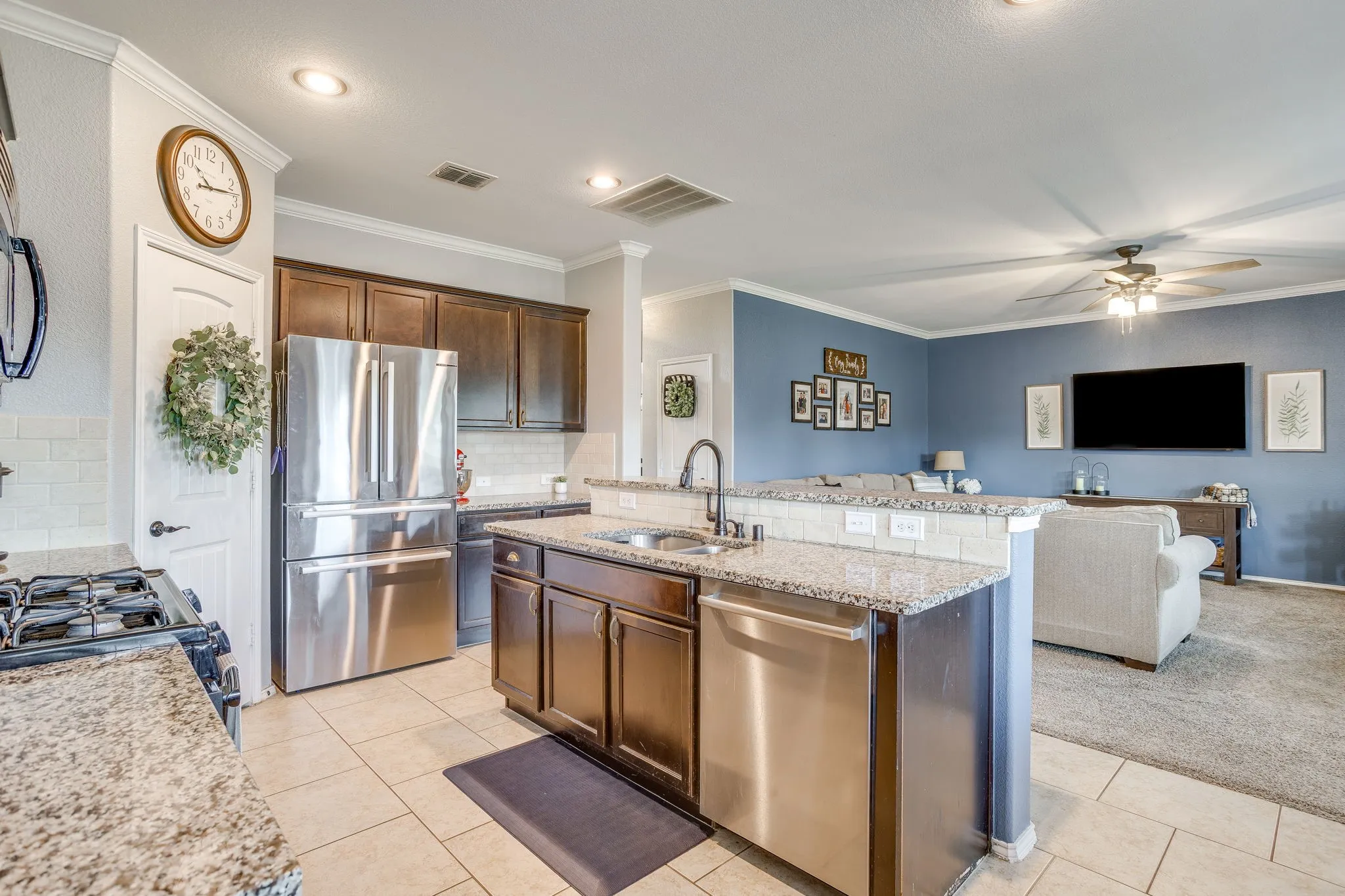 Kitchen with granite countertops, stainless steel appliances, dark wood cabinetry, tile flooring, and recessed lighting