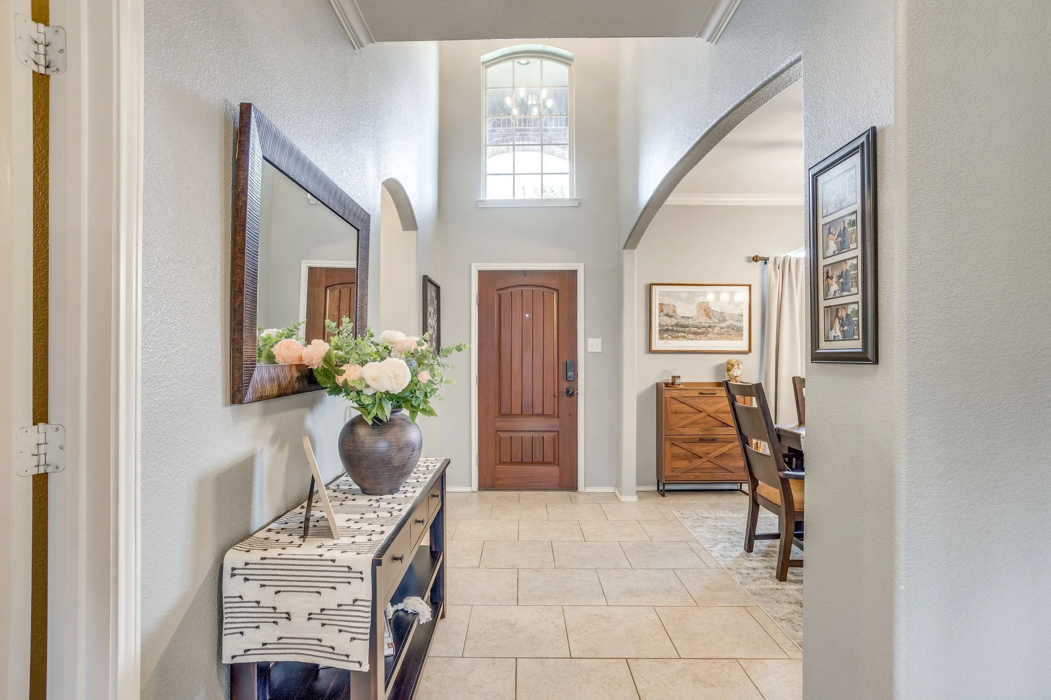 Two-story foyer with a wood-panel entry door, arched entryway, and tile flooring