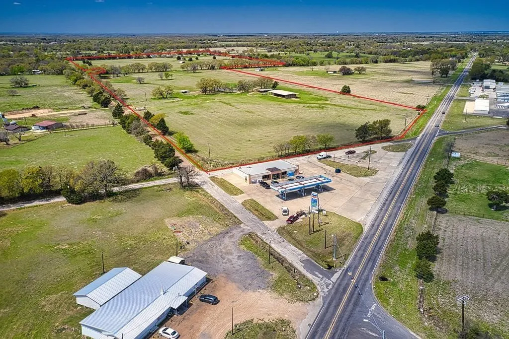 Expansive land parcel featuring open fields and mature trees, with direct road frontage