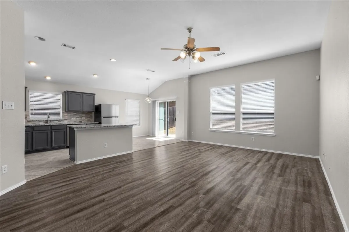 Wood-finish flooring, vaulted ceiling, ceiling fan, recessed lighting, and sliding glass door