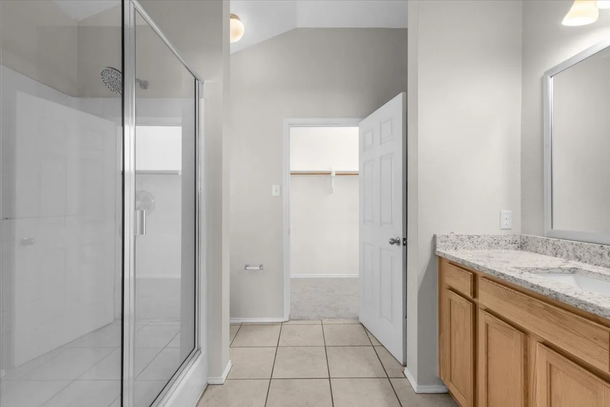 Walk-in shower with clear glass enclosure and tile surround
