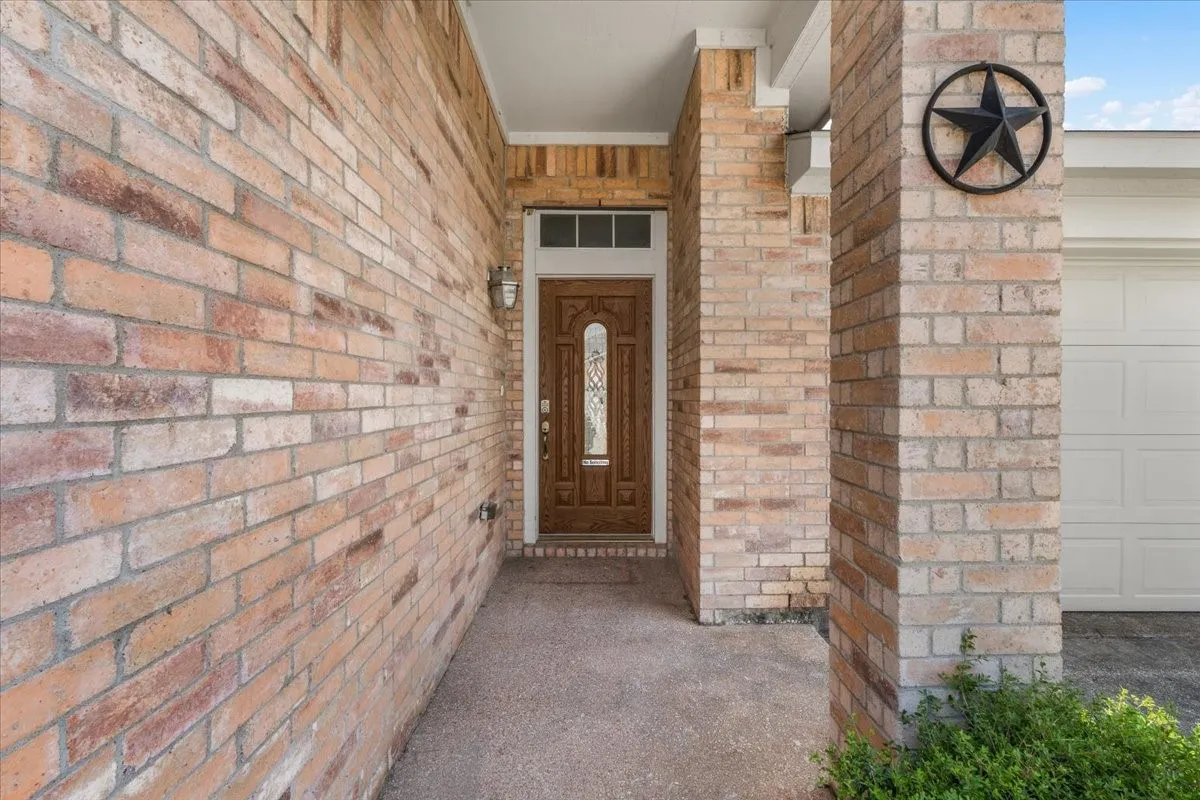 Brick facade with a covered entry, decorative wood door with glass paneling, and a white garage door