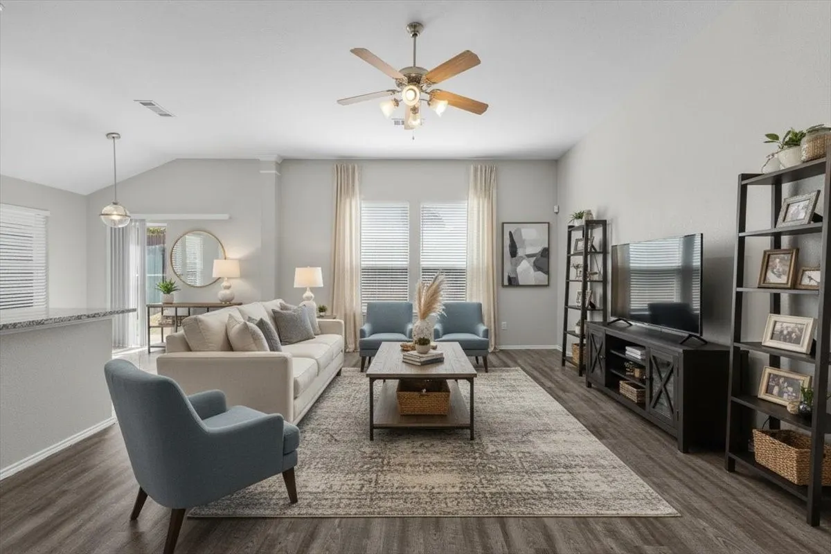 Vaulted ceiling with a ceiling fan, wood-finish flooring, two large windows with blinds, and a sliding glass door (virtually staged)