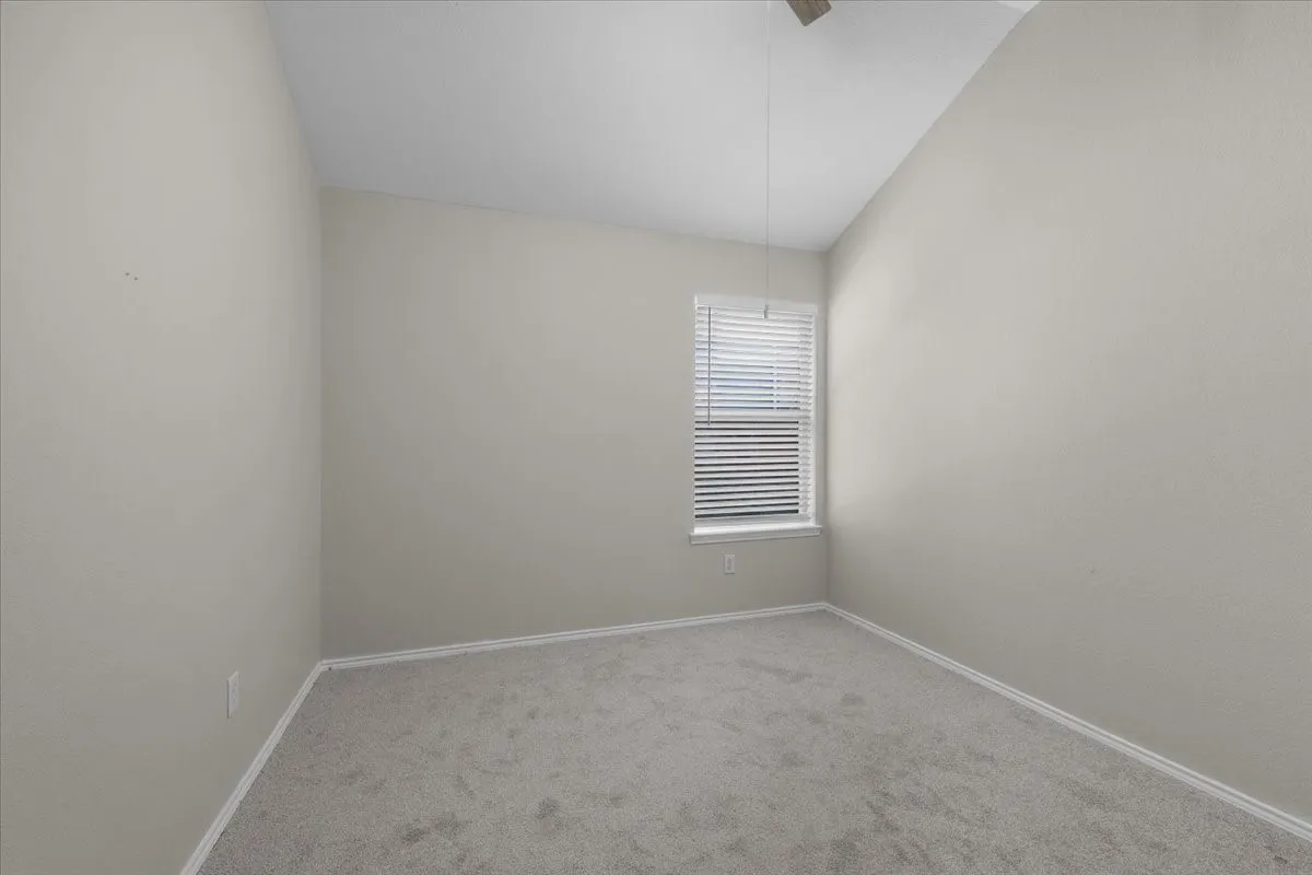 Neutral tone walls and carpeting with a window featuring horizontal blinds