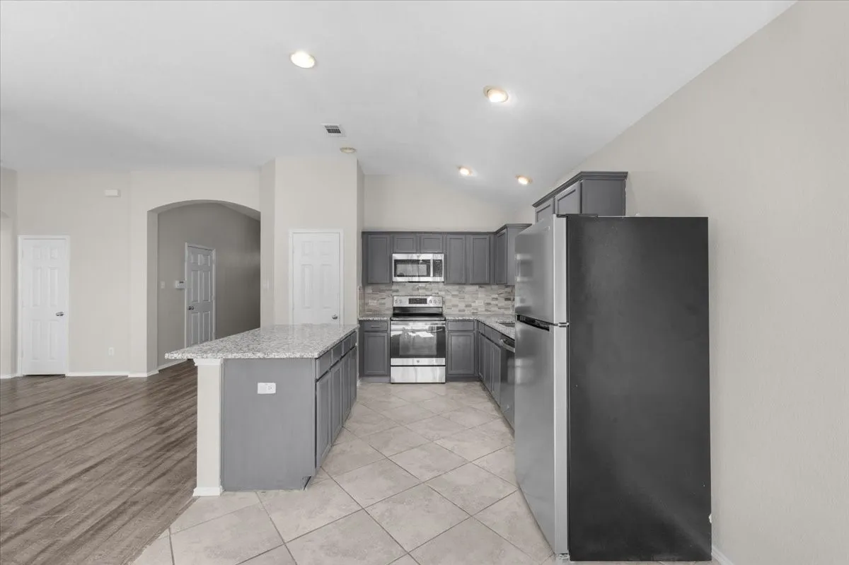 Kitchen featuring gray cabinetry, stainless steel appliances, a tiled backsplash, and recessed lighting