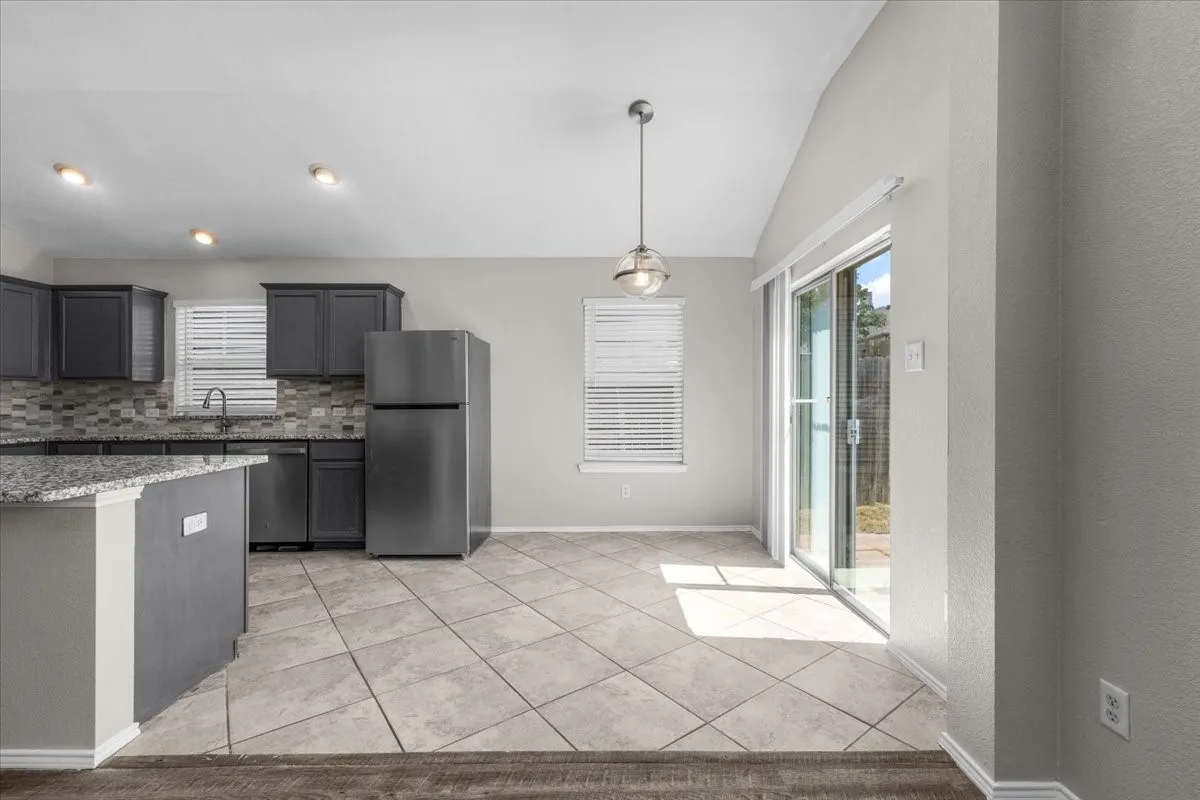 Kitchen featuring dark cabinetry, stainless steel appliances, speckled stone countertops, and a mosaic tile backsplash