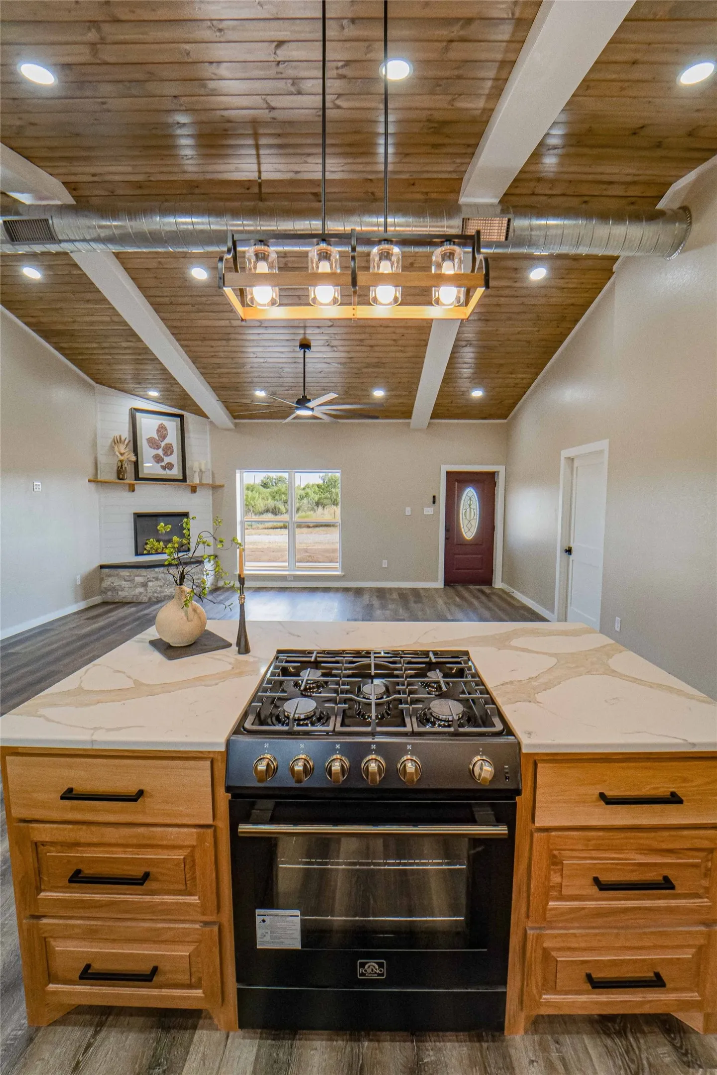 Kitchen island with a built-in range, wood cabinetry, and a light-colored countertop