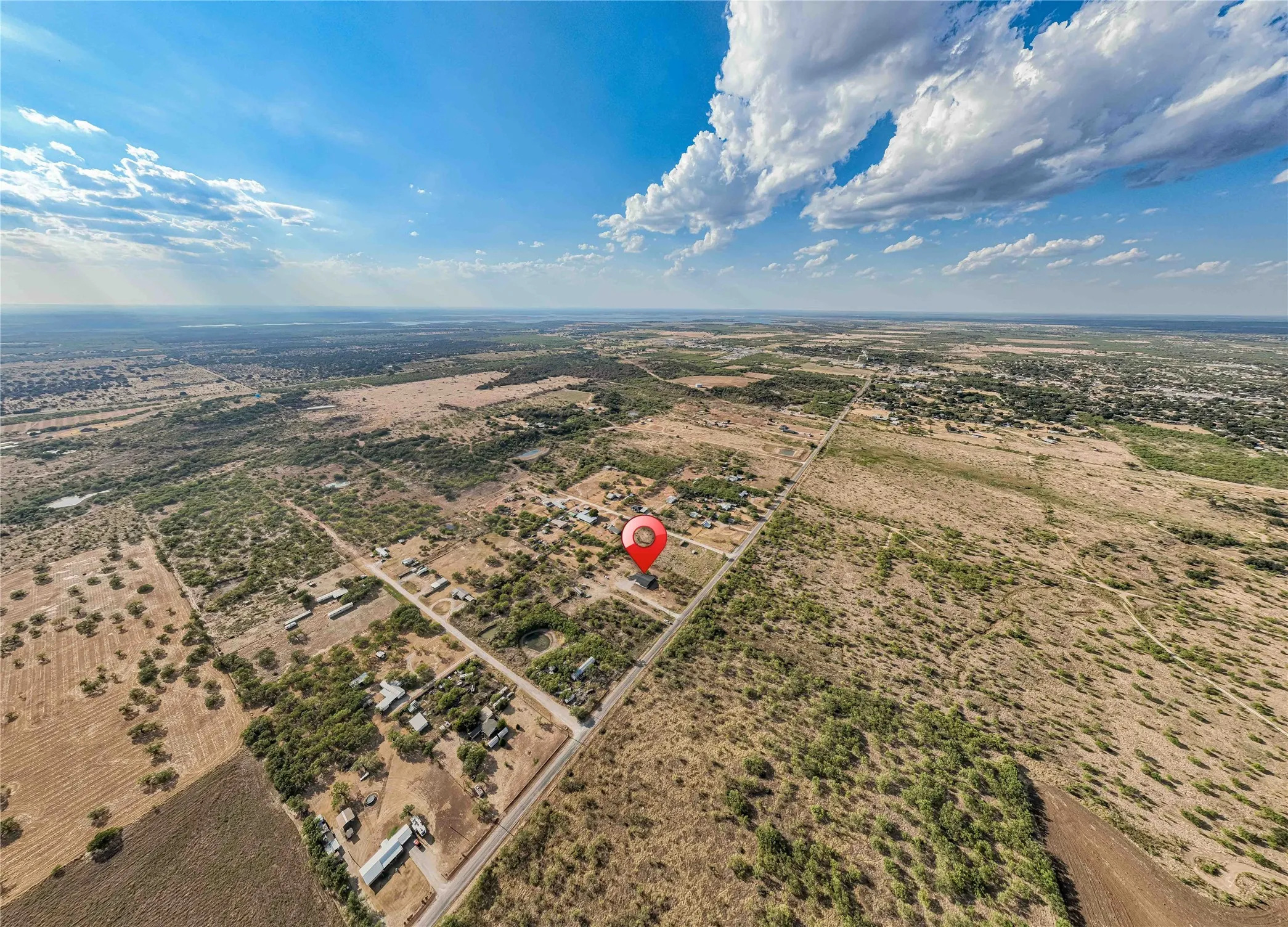 Expansive aerial perspective showcasing a rural landscape with scattered properties and roadways under a clear sky