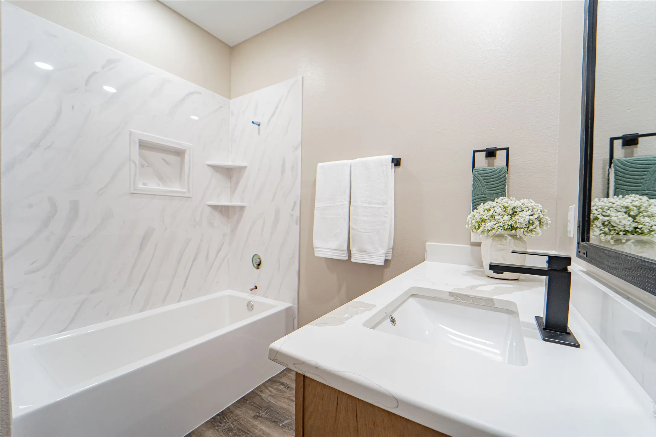 White bathtub with a tiled surround featuring an integrated niche and shelves