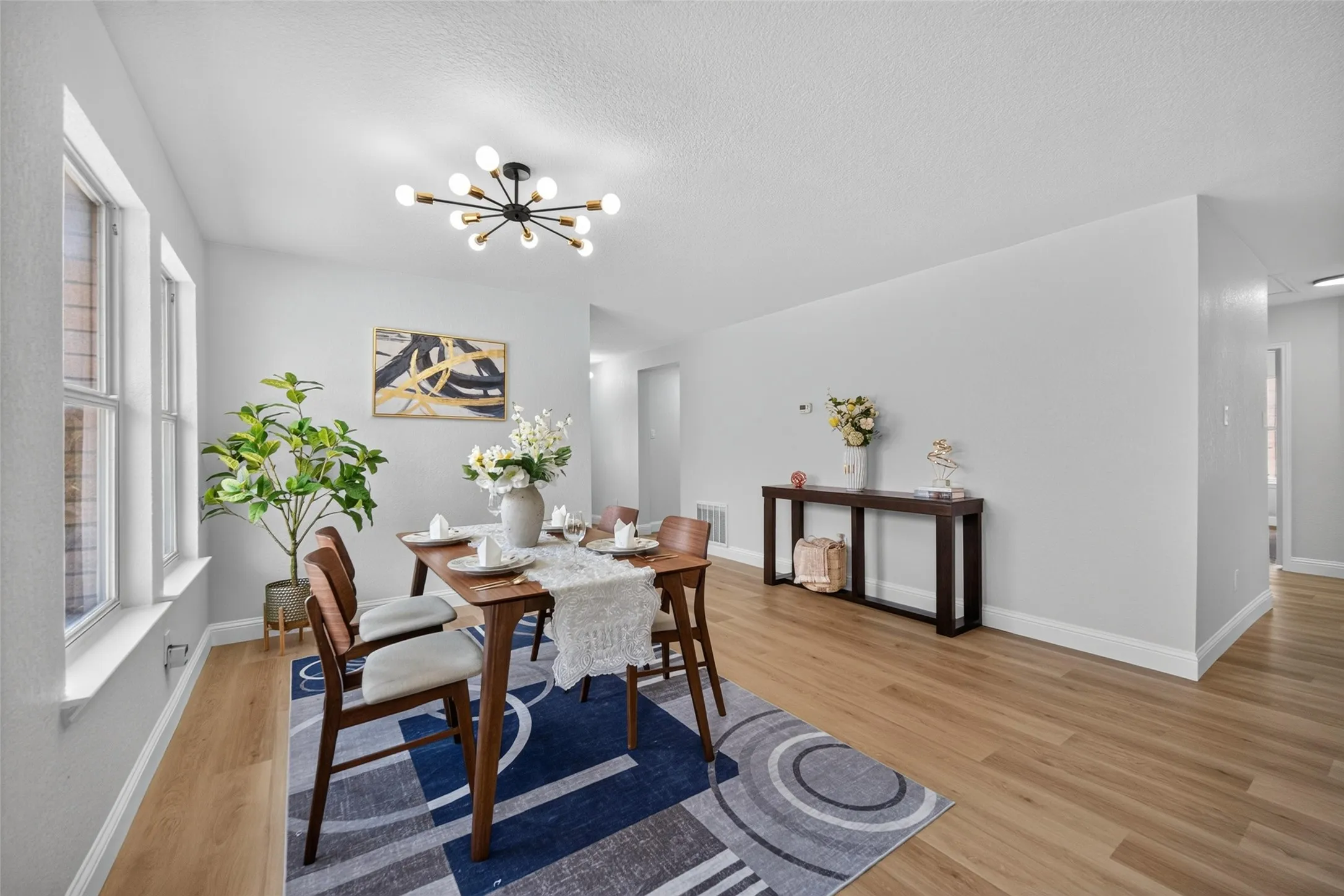 Bright interior with wood-finish flooring, multiple windows, and a contemporary ceiling fixture