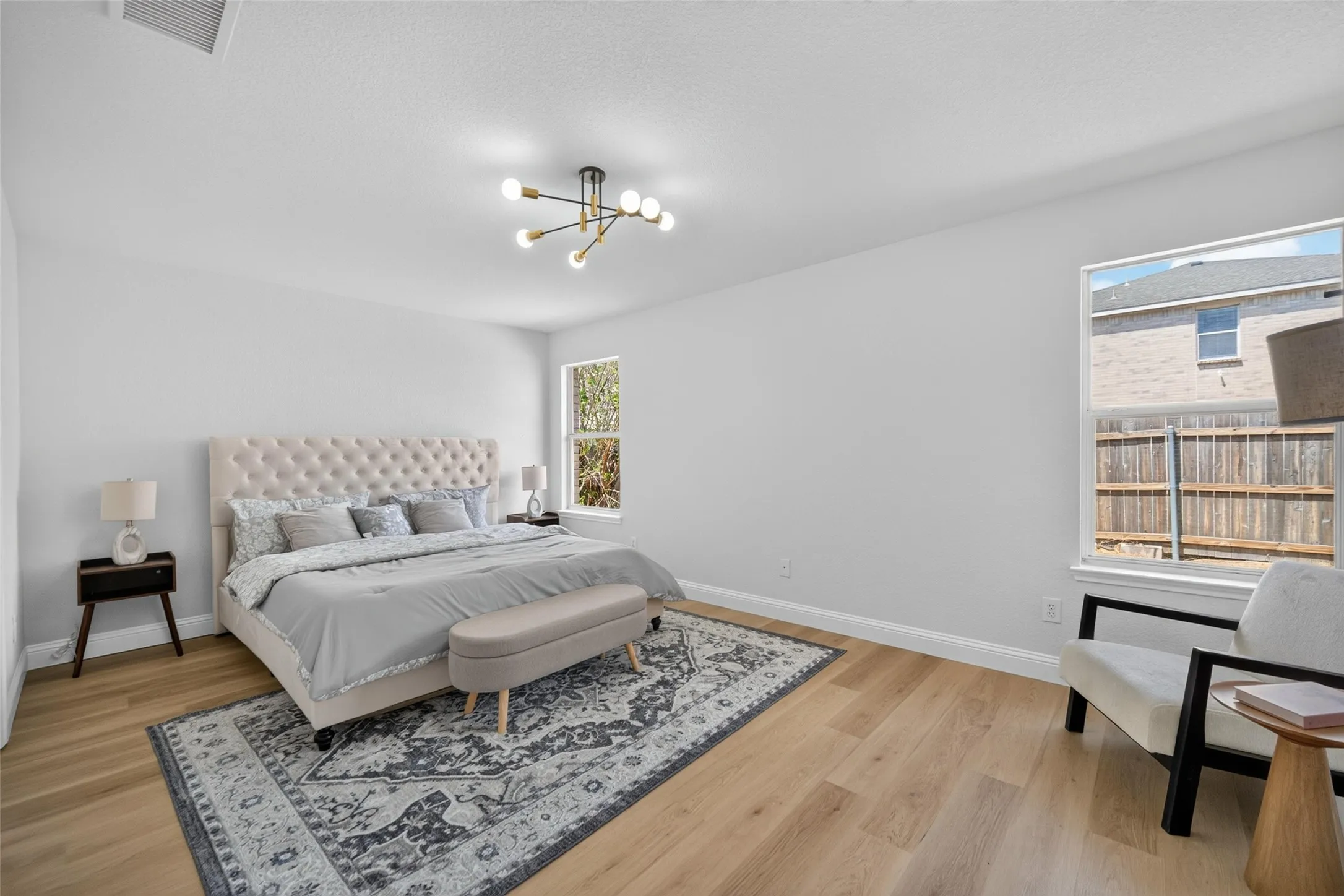 Wood-finish flooring, a contemporary chandelier, and multiple windows providing natural light