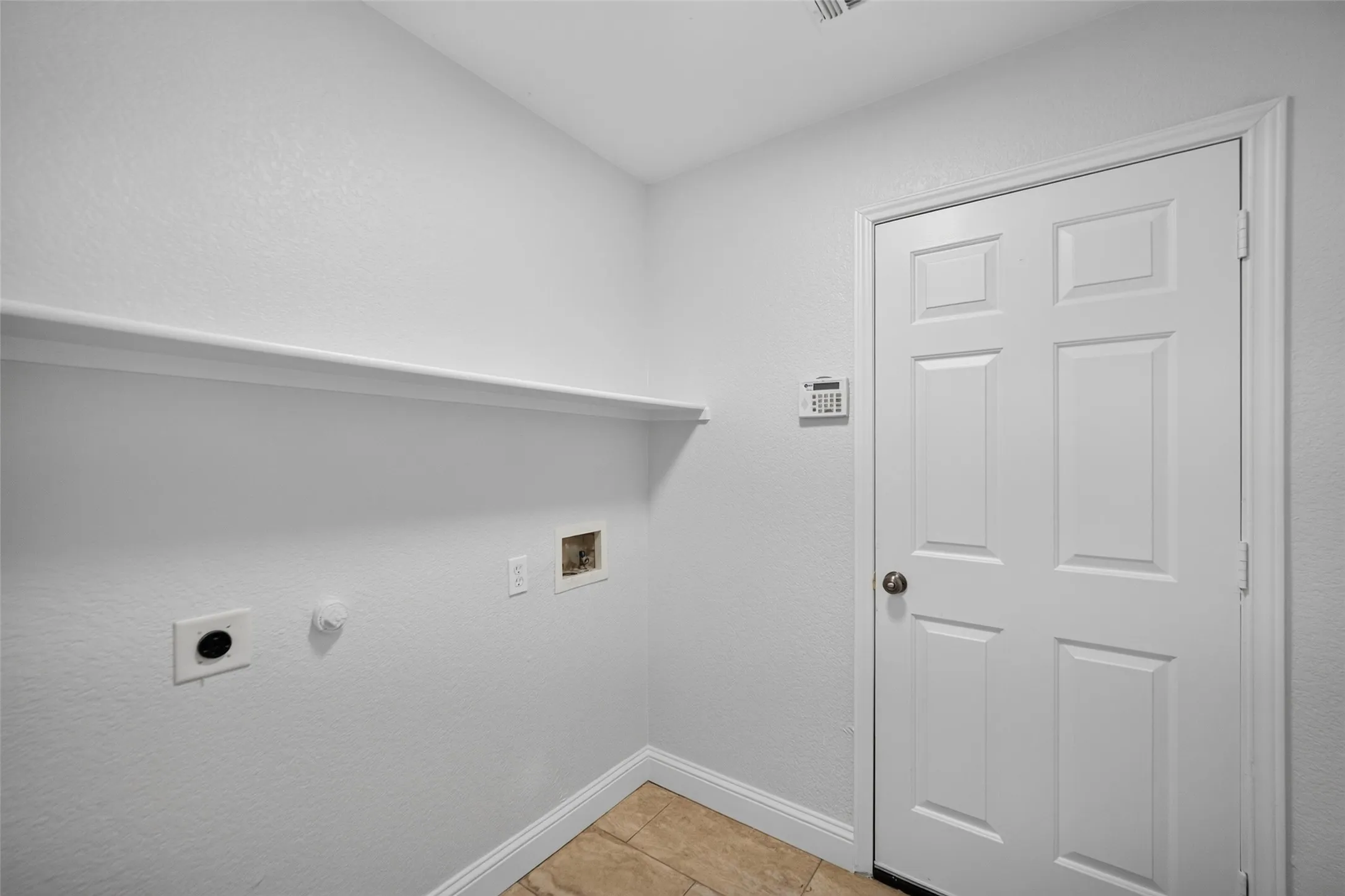 Utility area with a built-in shelf, neutral wall tones, and tiled flooring