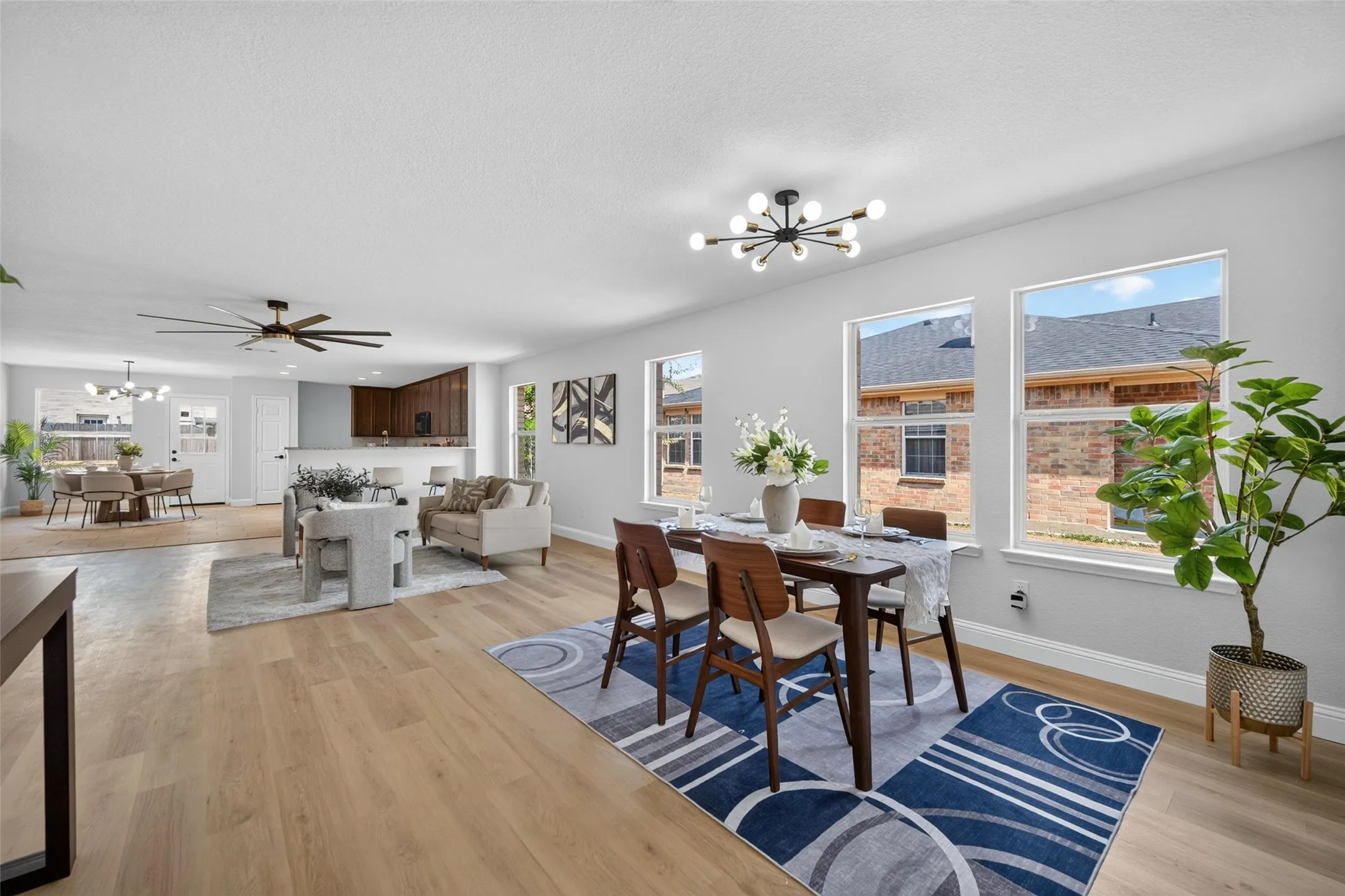 Light-toned wood-finish flooring throughout, multiple large windows, recessed lighting, and a contemporary chandelier