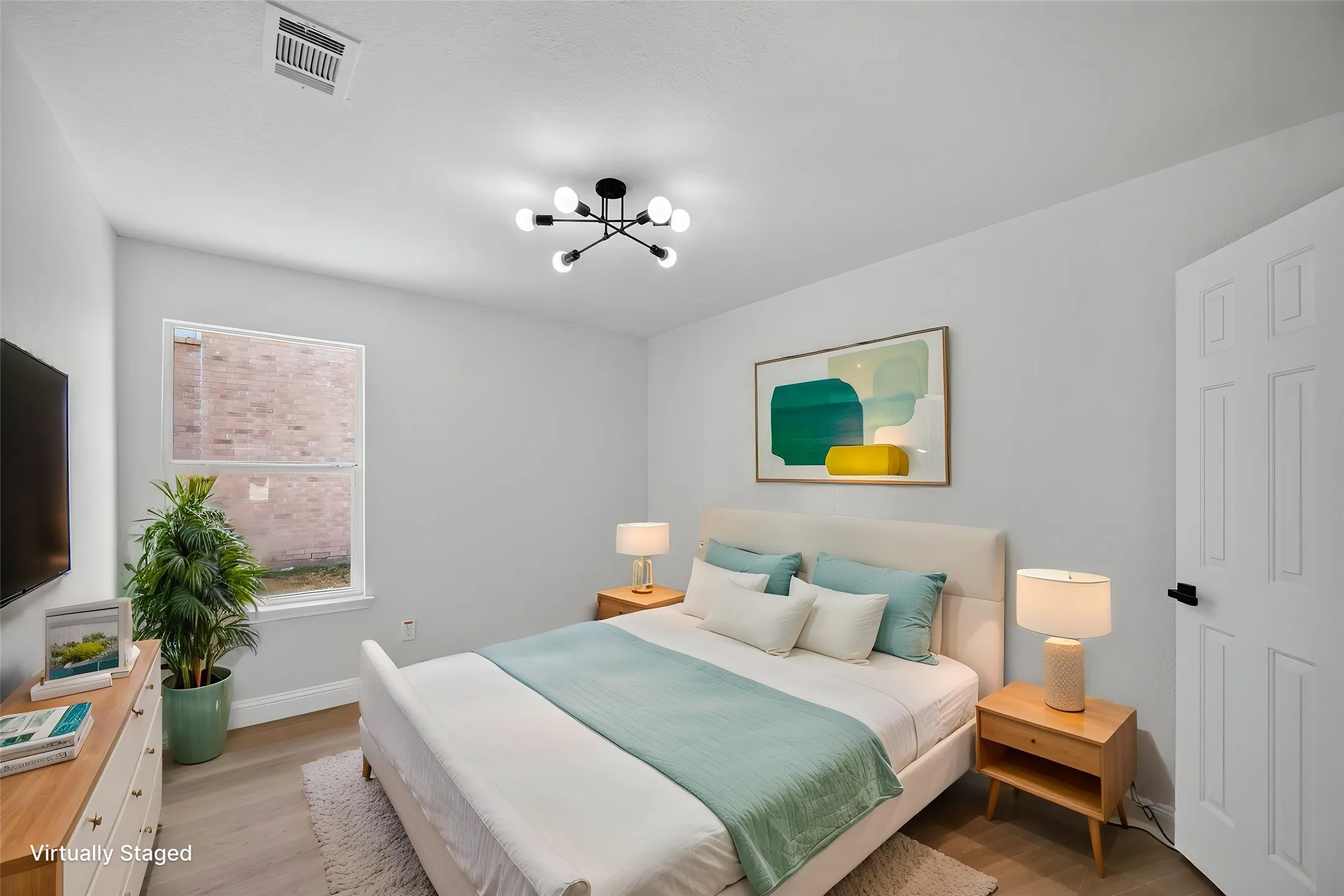 Spacious room featuring wood-finish flooring, a white paneled door with black hardware, and a window for natural light