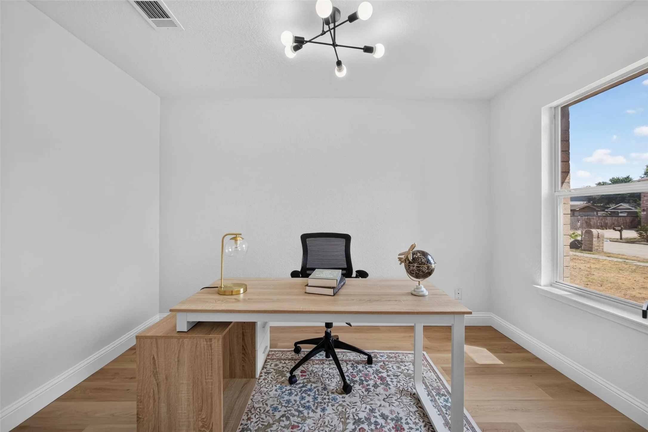 Recessed lighting, wood-finish flooring, and a contemporary ceiling fixture create a versatile interior
