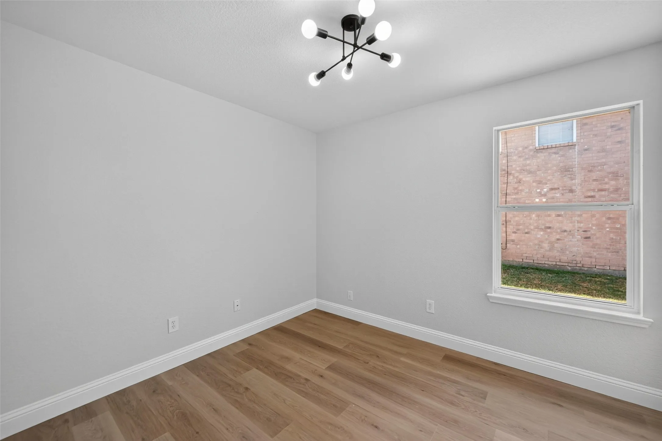 Wood-finish flooring, contemporary ceiling light fixture, and a single window