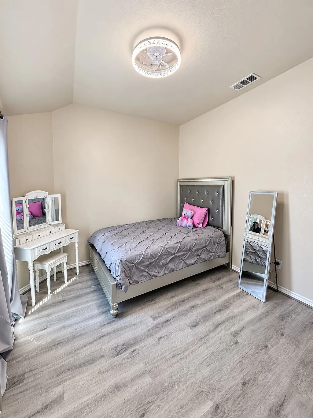 Neutral wall paint, wood-finish flooring, and a ceiling-mounted light fixture with fan