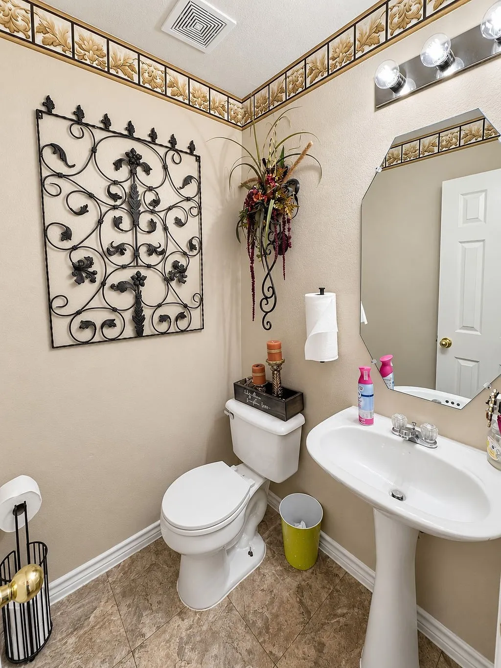 Pedestal sink with chrome faucet, octagonal mirror, and vanity light fixture with three exposed bulbs