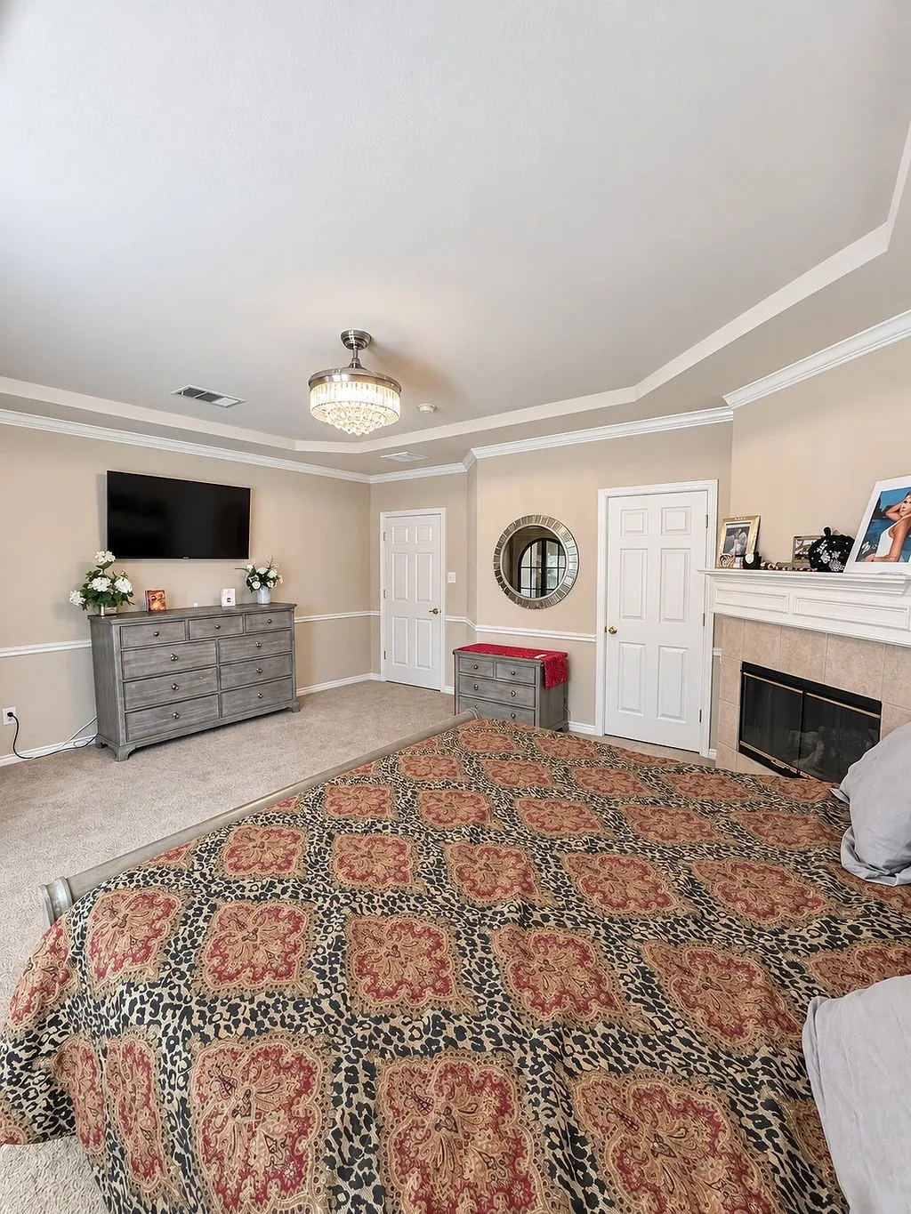 Tray ceiling with decorative crown molding, recessed lighting, and a crystal chandelier
