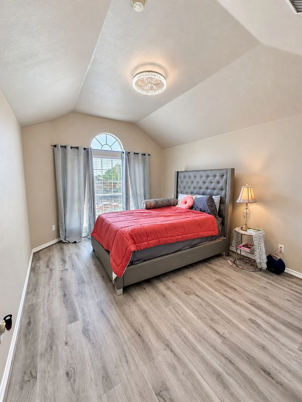 Vaulted ceiling, wood-finish flooring, and arched window with blinds