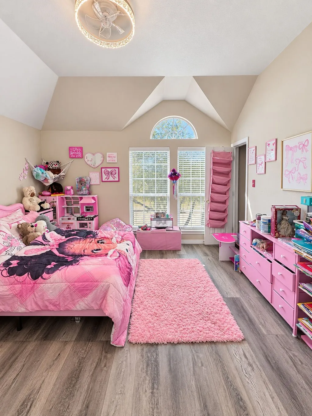 Vaulted ceiling with an arched window, wood-finish flooring, and a ceiling fan with integrated lighting