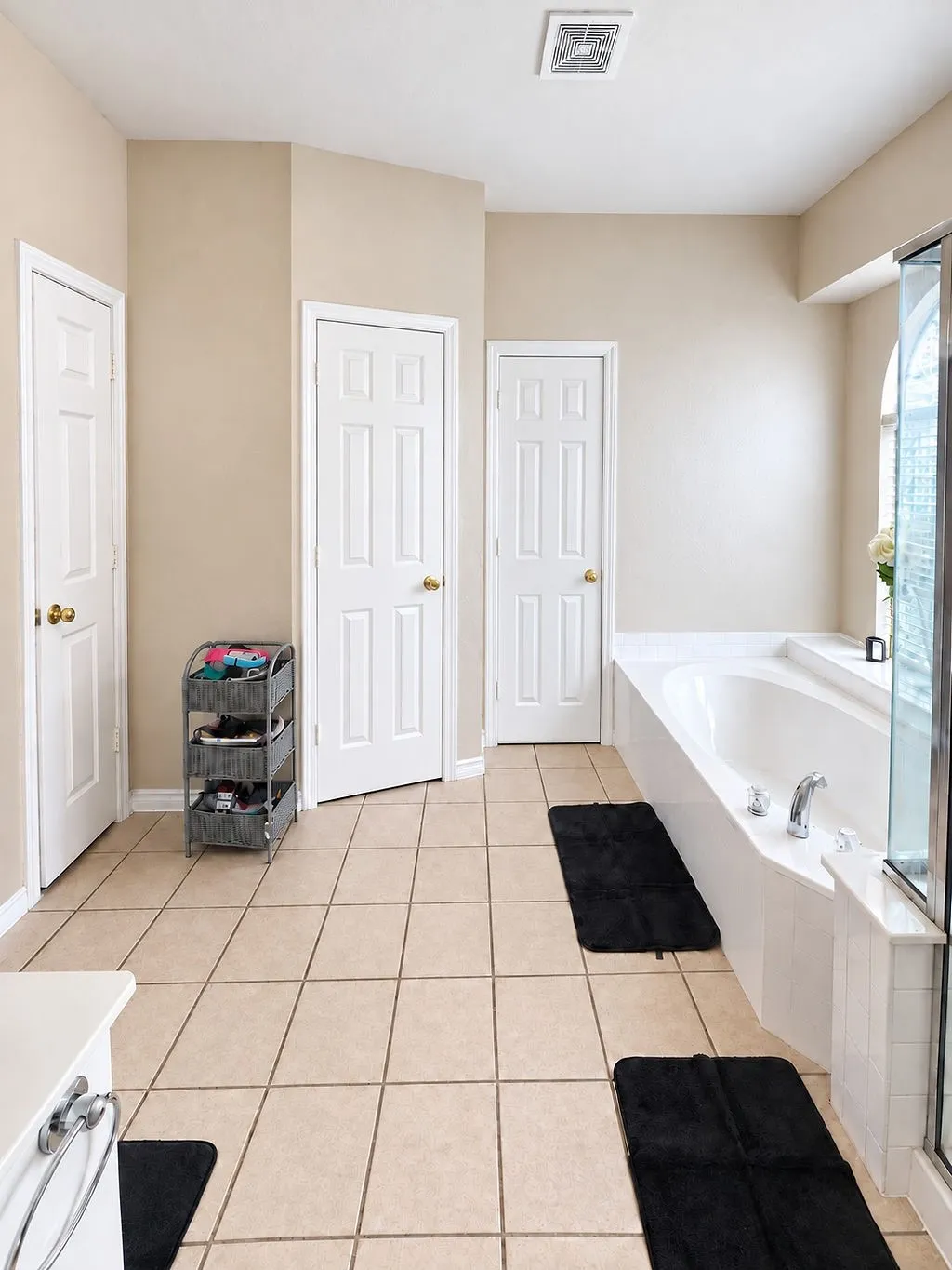 Spacious bathroom with neutral tile flooring, a built-in soaking tub, and multiple panel doors