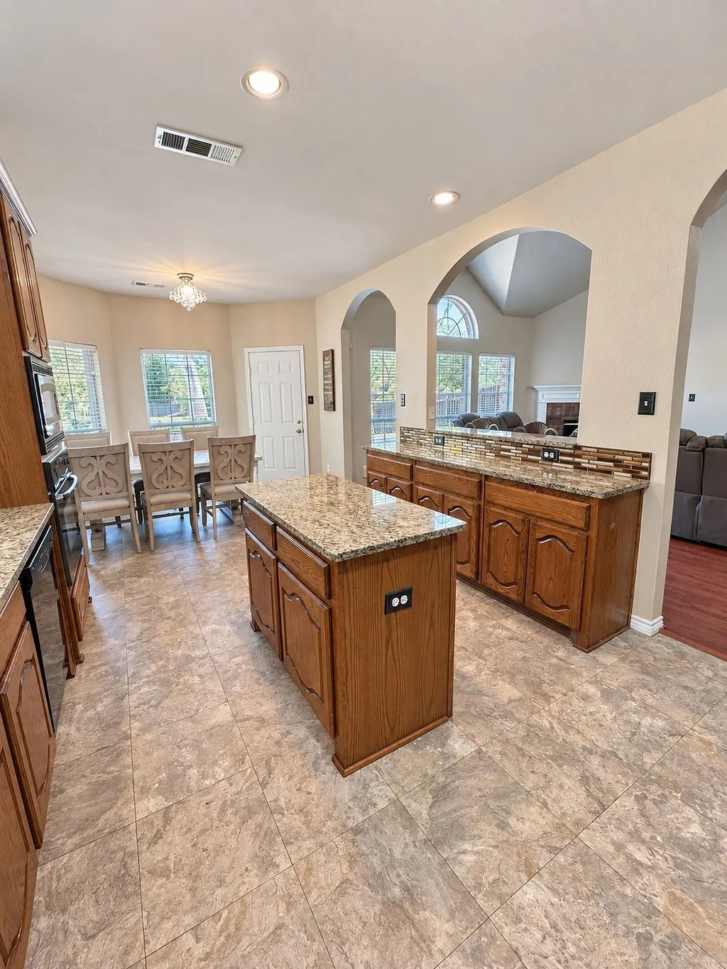 Kitchen featuring a central island, wood-finish cabinetry, stone countertops, and tile flooring