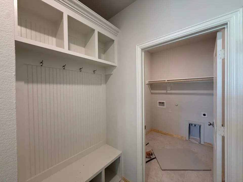 Built-in storage bench with beadboard backing, overhead shelving, and coat hooks