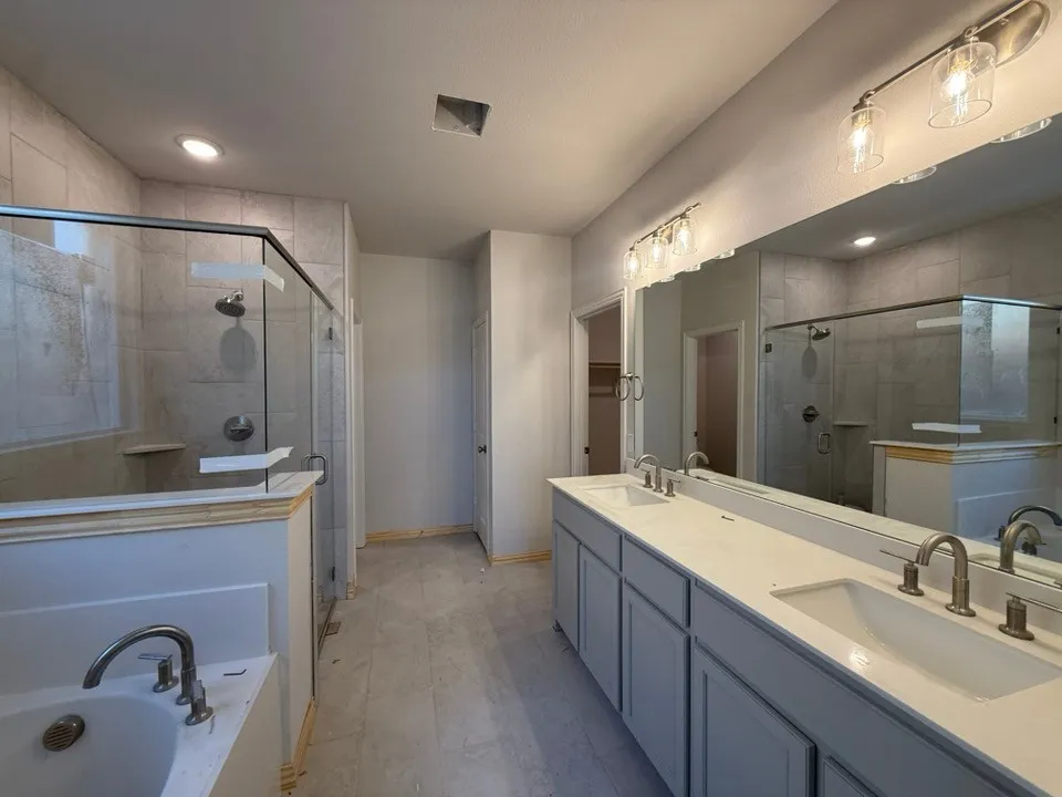 Dual vanity with undermount sinks, frameless glass shower enclosure, and a built-in bathtub
