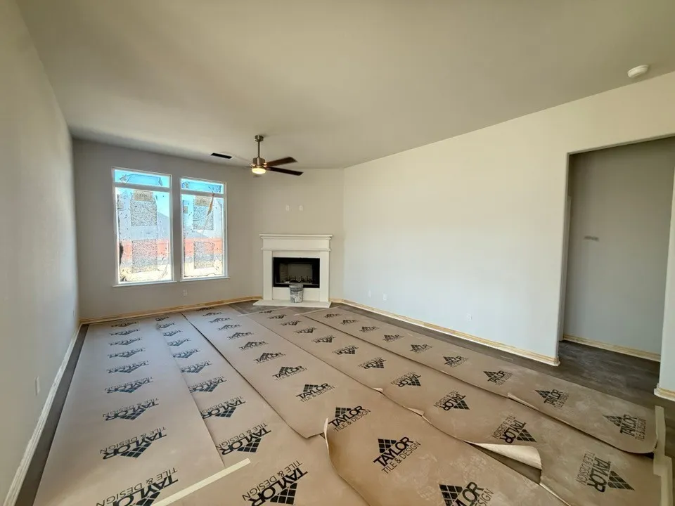 Spacious living area featuring a fireplace with a mantel, multiple windows, and a ceiling fan