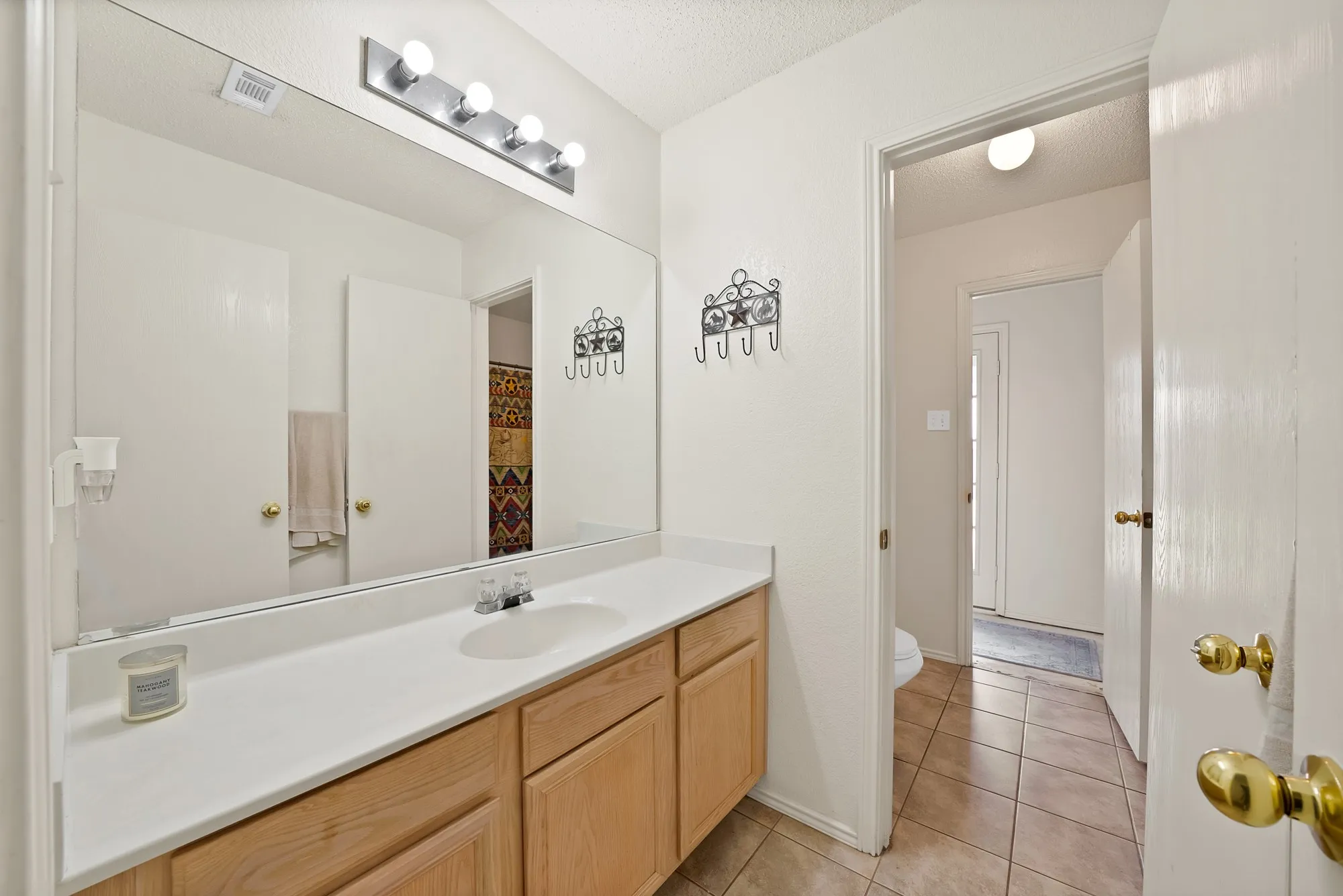 Bathroom featuring a vanity with wood-finish cabinetry, a large wall-mounted mirror, and tile flooring