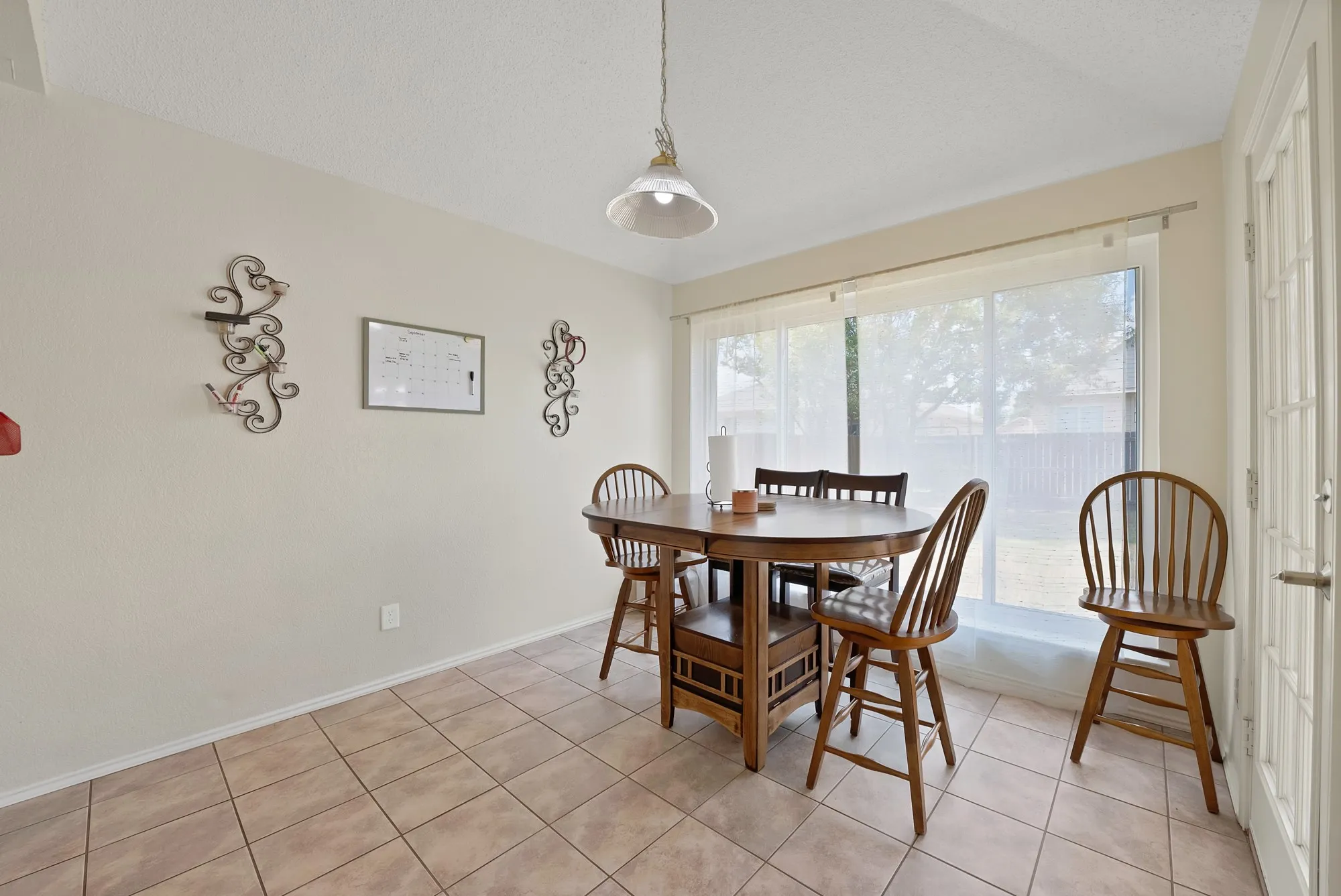 Tile flooring, large window with sheer blinds, pendant light fixture, French door with glass panels, painted walls
