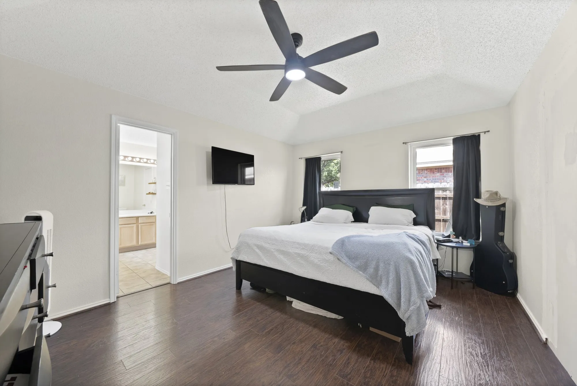 Vaulted ceiling with an integrated ceiling fan, wood-finish flooring, and recessed windows