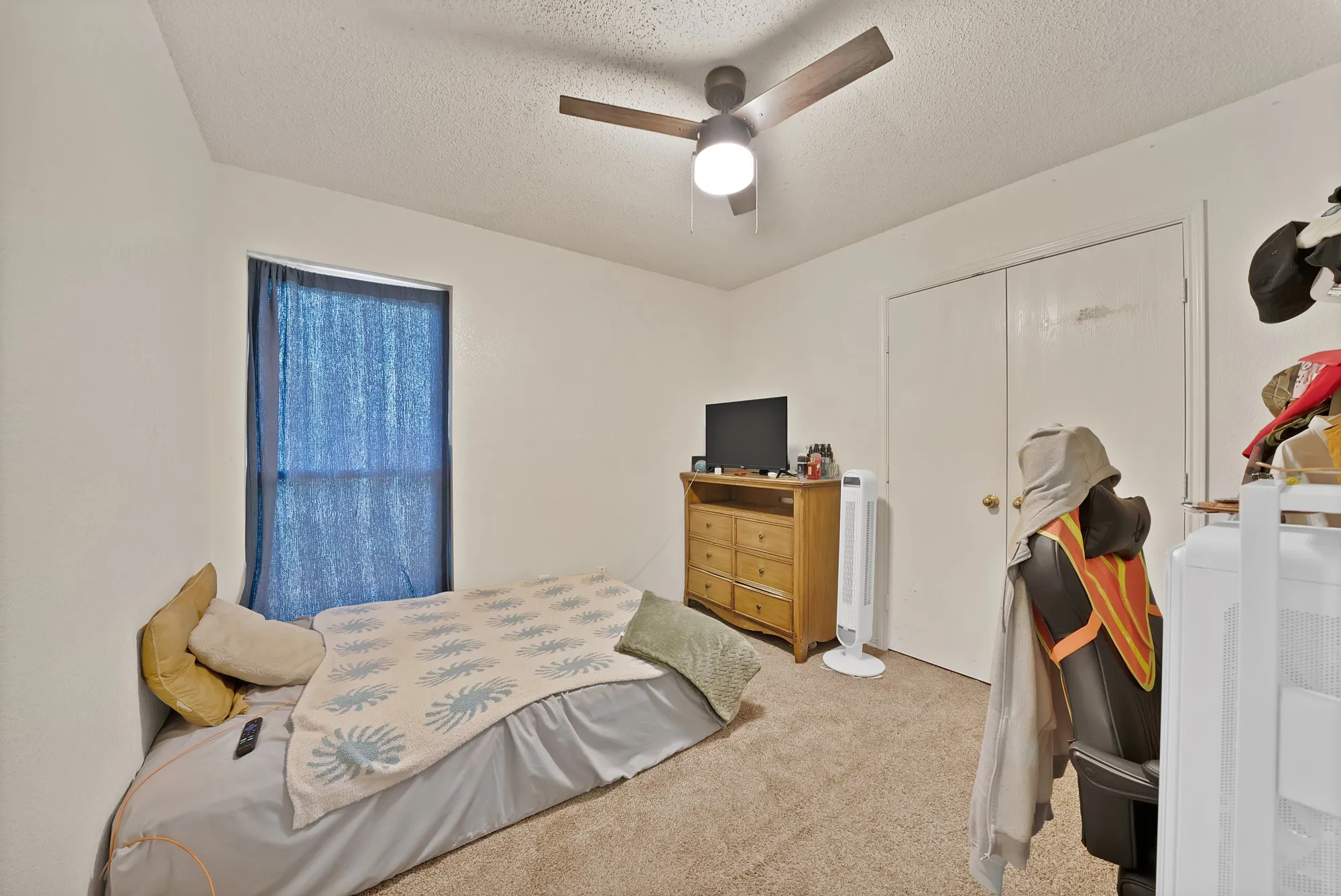 Carpeted room with a ceiling fan, a window, and a built-in closet with double doors