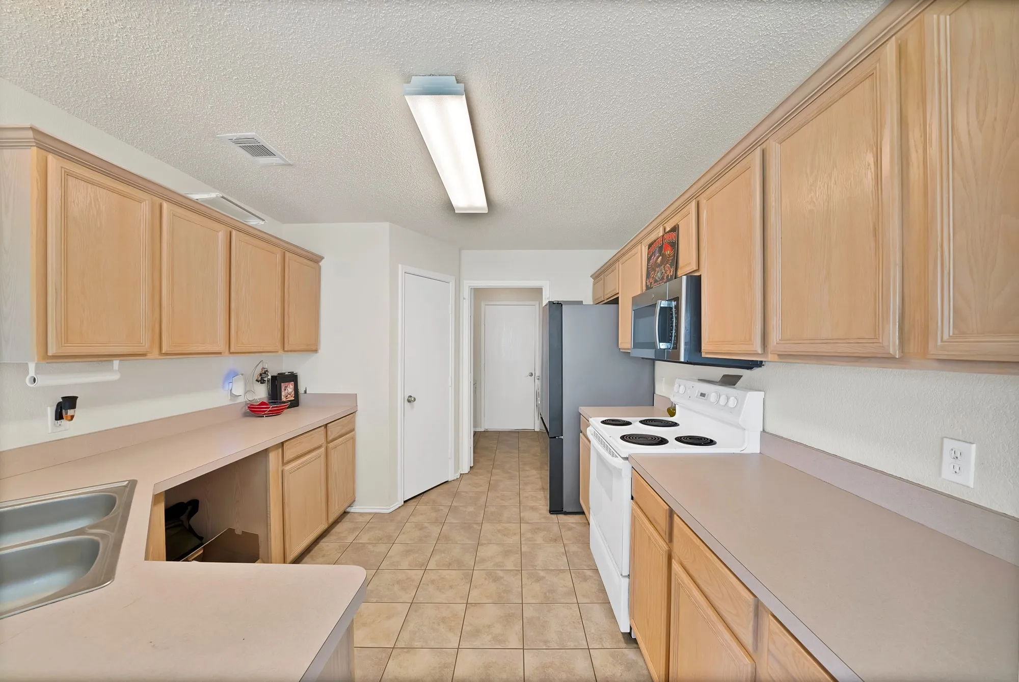 Kitchen featuring wood-finish cabinetry, tile flooring, and integrated stainless steel microwave