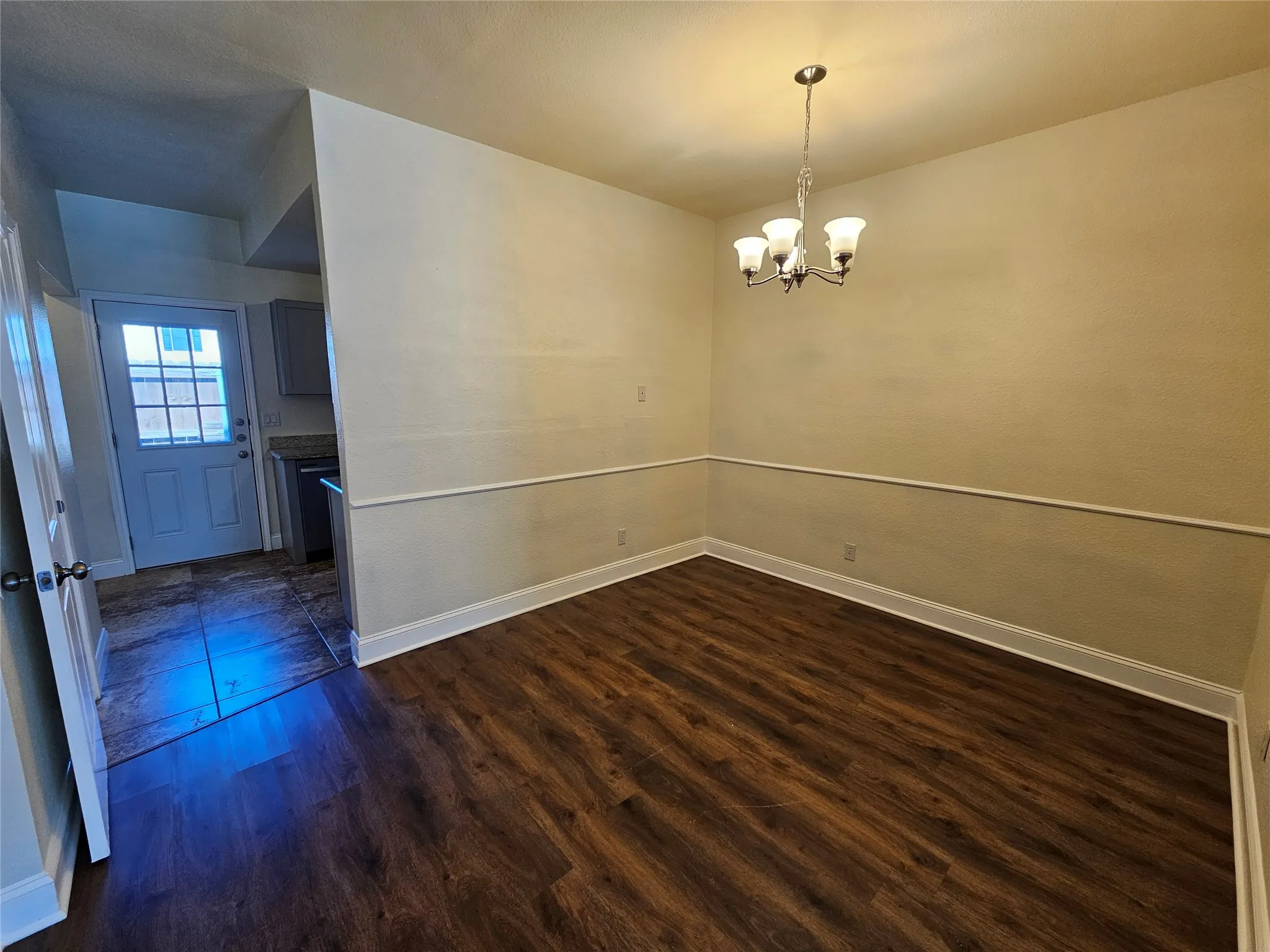 Wood-finish flooring, crown molding, and a four-light chandelier