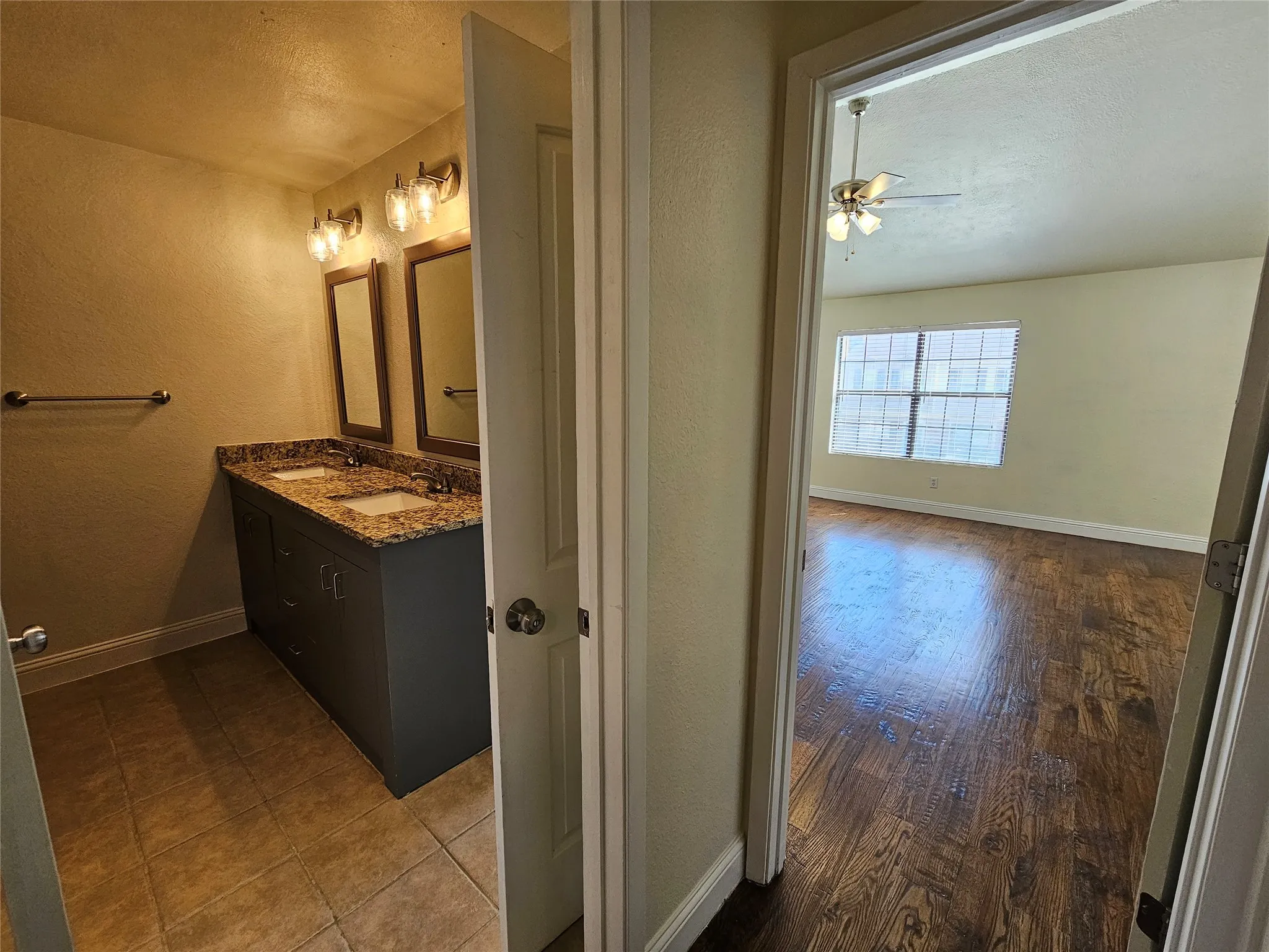 Bathroom vanity with dual sinks, granite countertop, and tiled flooring