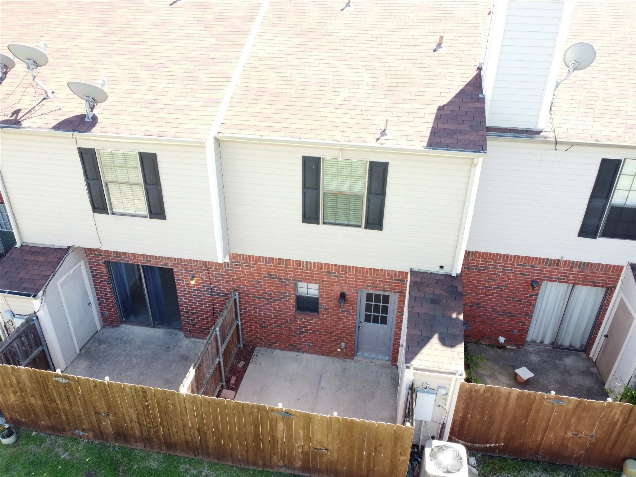 Brick and siding exterior with concrete patios and fenced outdoor spaces