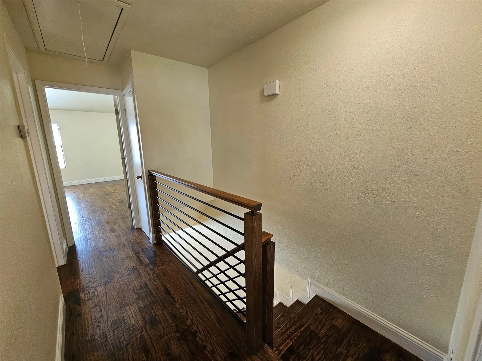 Hardwood flooring throughout, modern horizontal metal railing, and staircase with wood treads