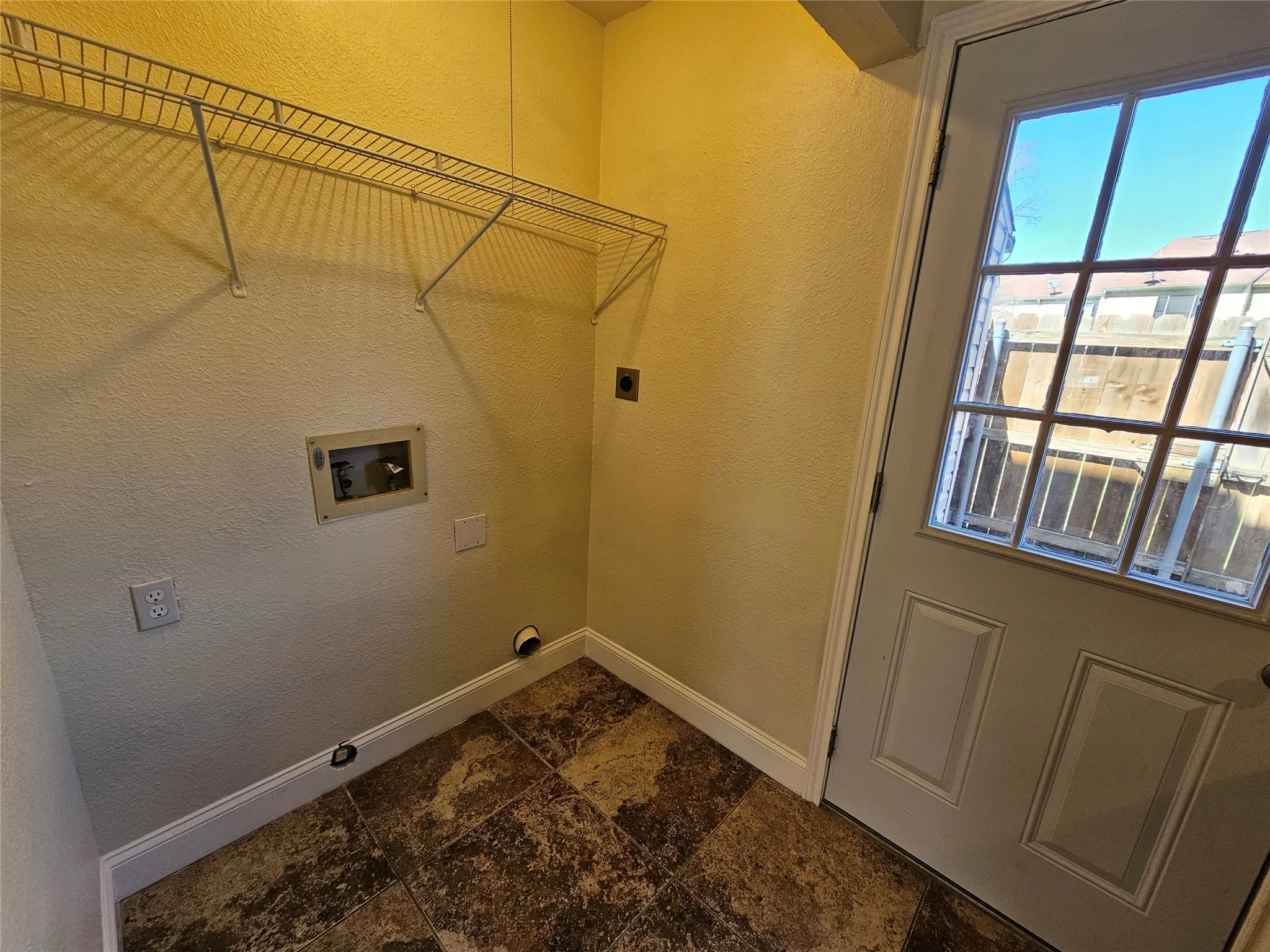 Utility space featuring a glass-paned door, wire shelving, and durable floor tiling