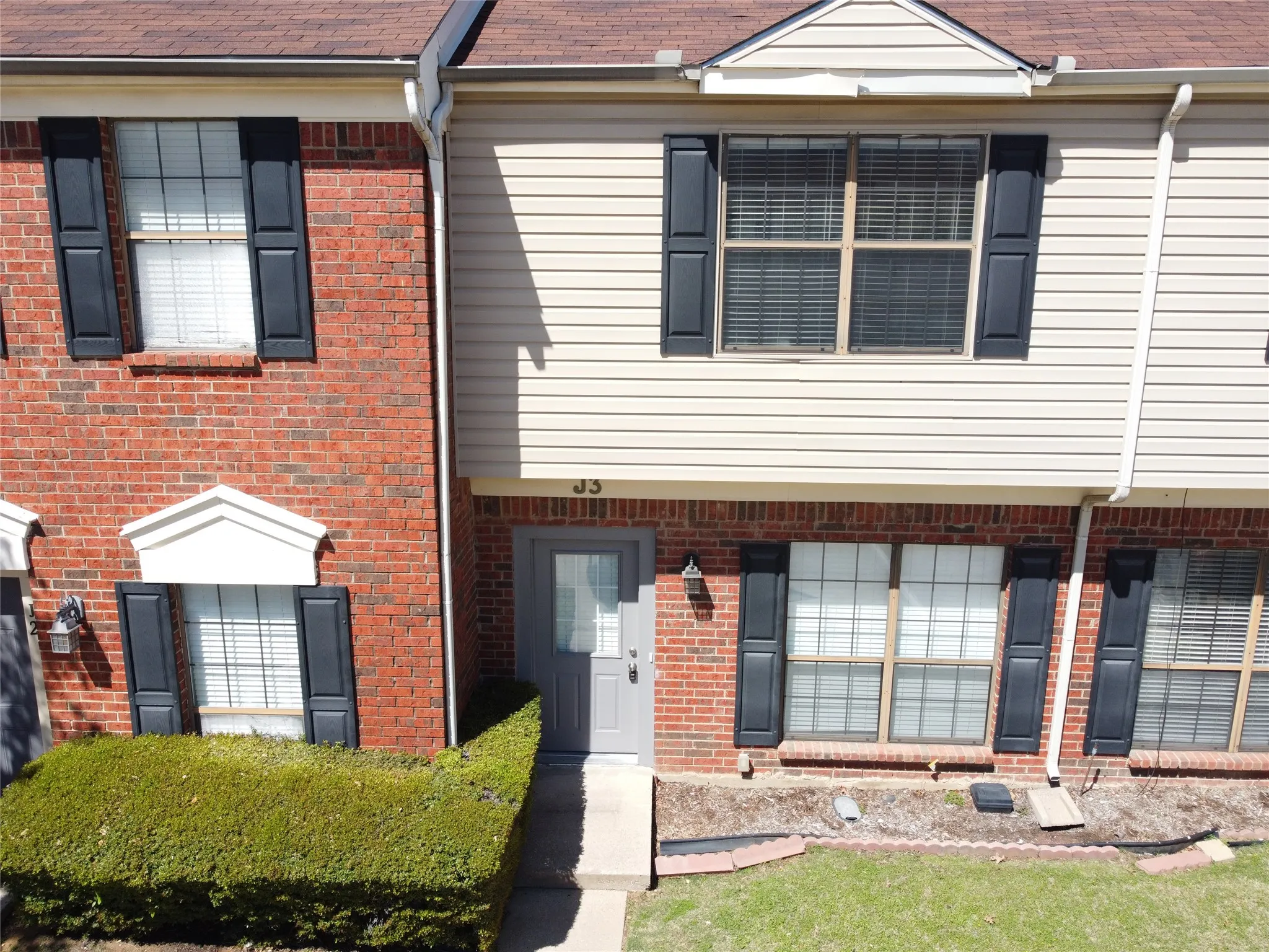Brick and siding exterior with dark shutters, featuring a prominent front entry door