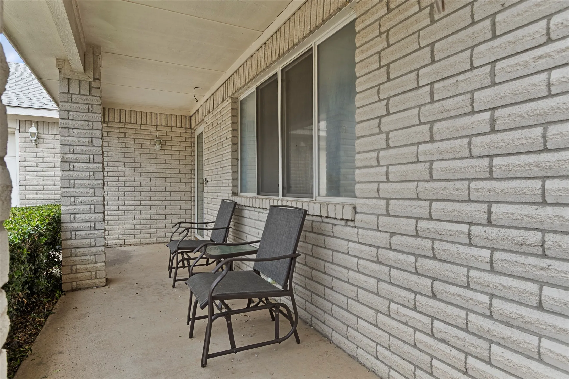 Covered front porch with light-colored brick facade