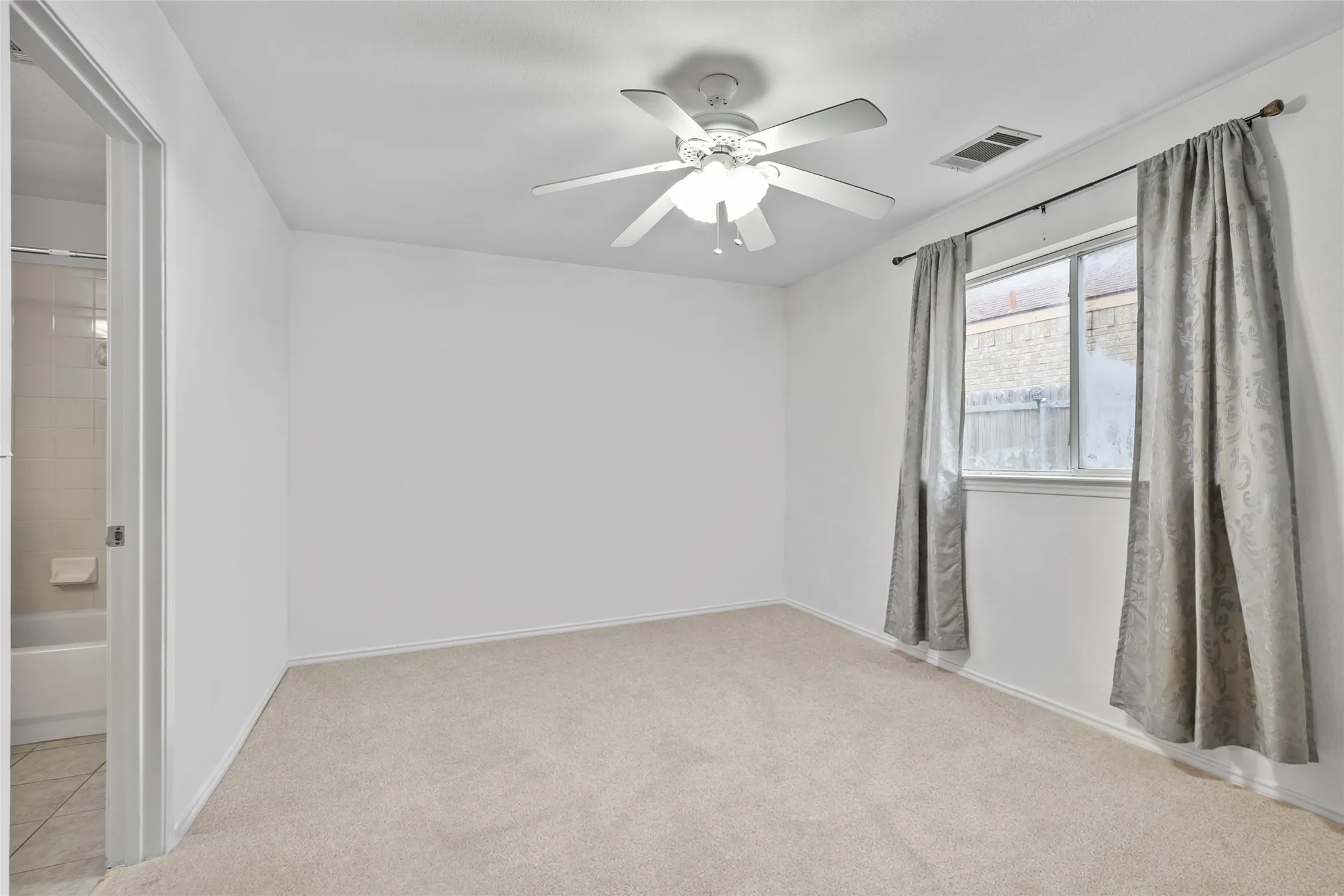 STAGE Neutral wall color, ceiling fan, window with curtains, and carpet flooring