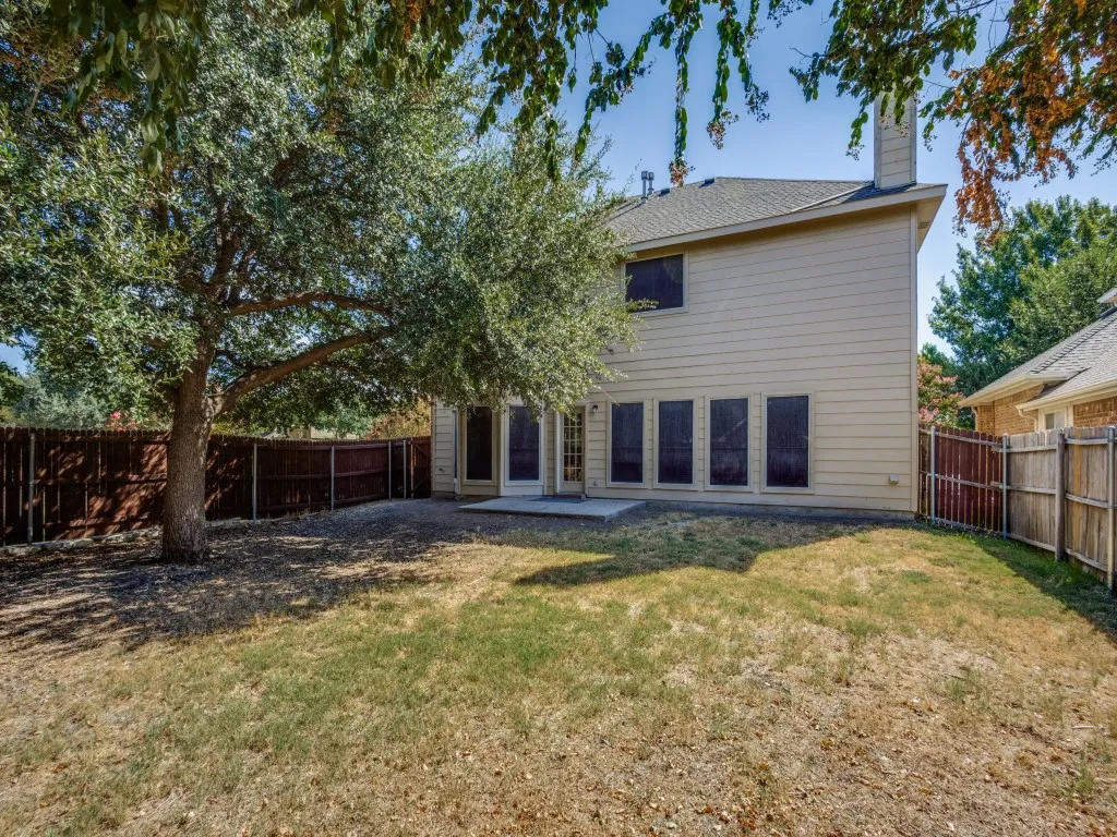 Expansive backyard featuring a mature tree, privacy fencing, and a concrete patio