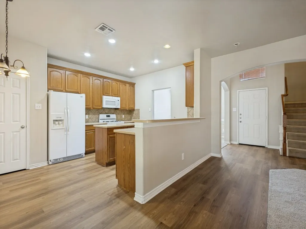 Kitchen featuring wood-finish flooring, wood cabinetry, tile backsplash, and recessed lighting