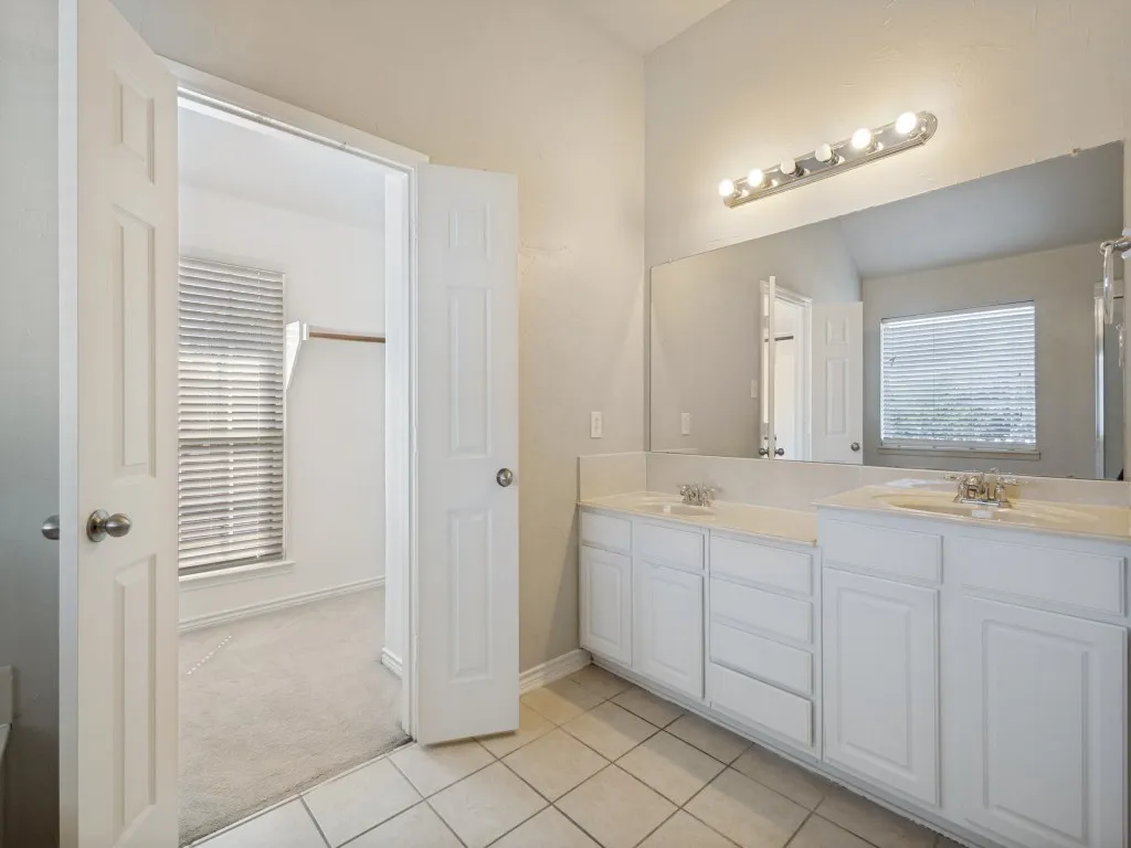 Dual vanity with white cabinetry, integrated sinks, large mirror, and overhead lighting
