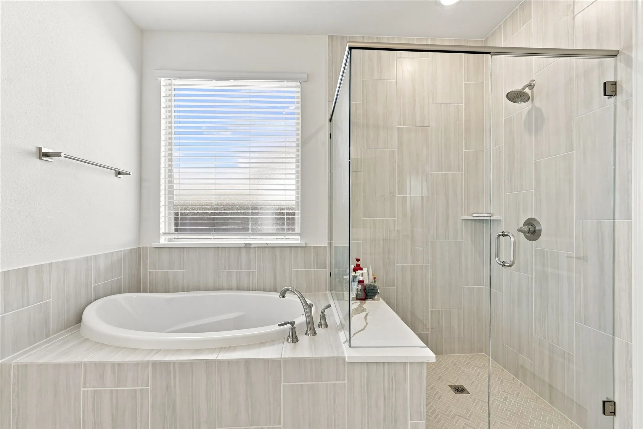 Built-in soaking tub with brushed nickel fixtures, tiled surround, and window with blinds