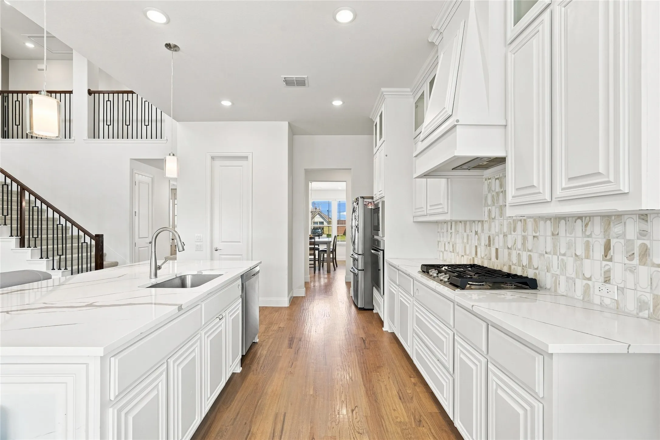 Gourmet kitchen featuring white cabinetry, light-toned countertops, a gas cooktop, and a mosaic tile backsplash