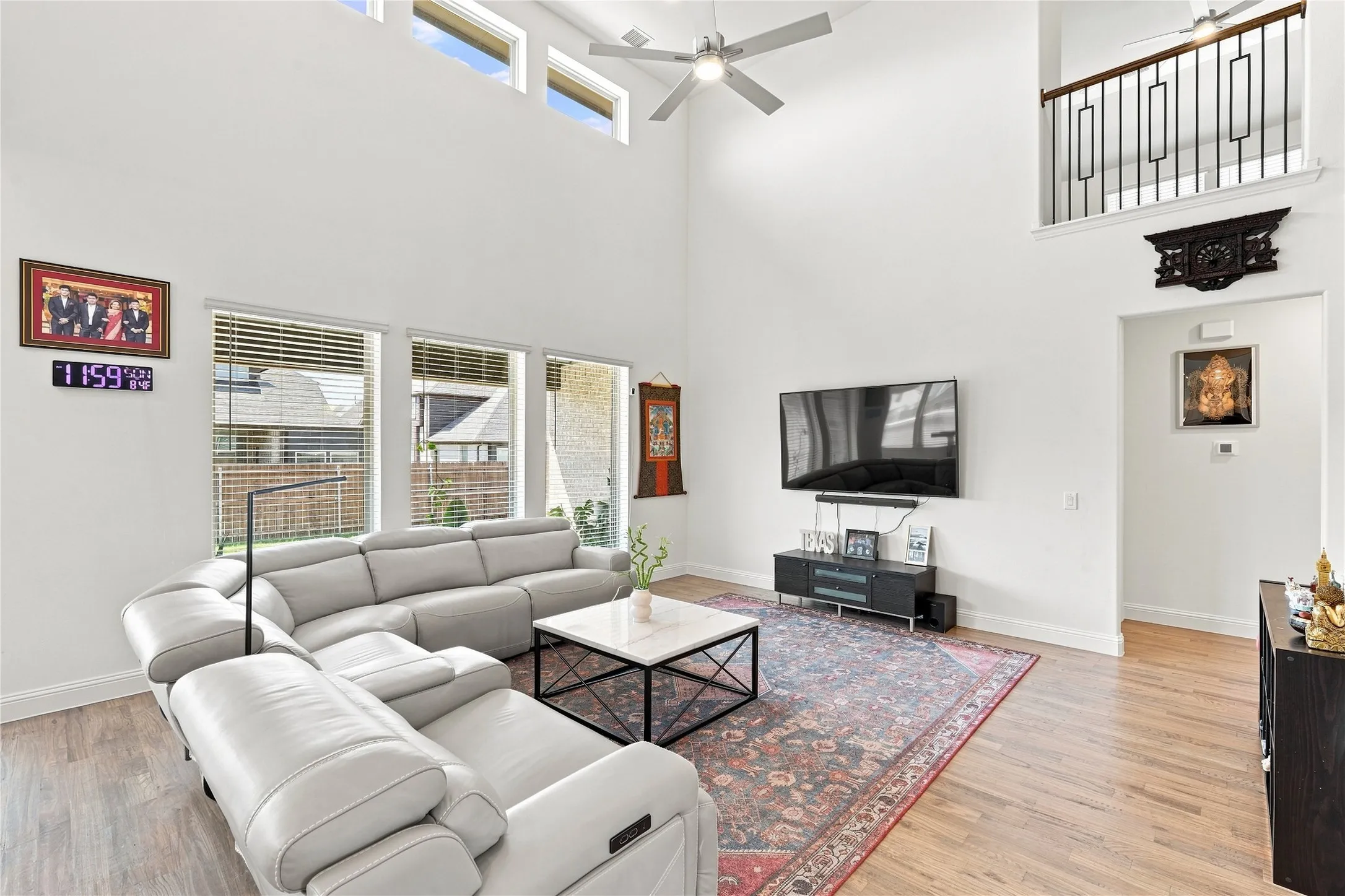 Soaring ceiling with high transom windows, wood-finish flooring, and an open balcony overlooking the living area