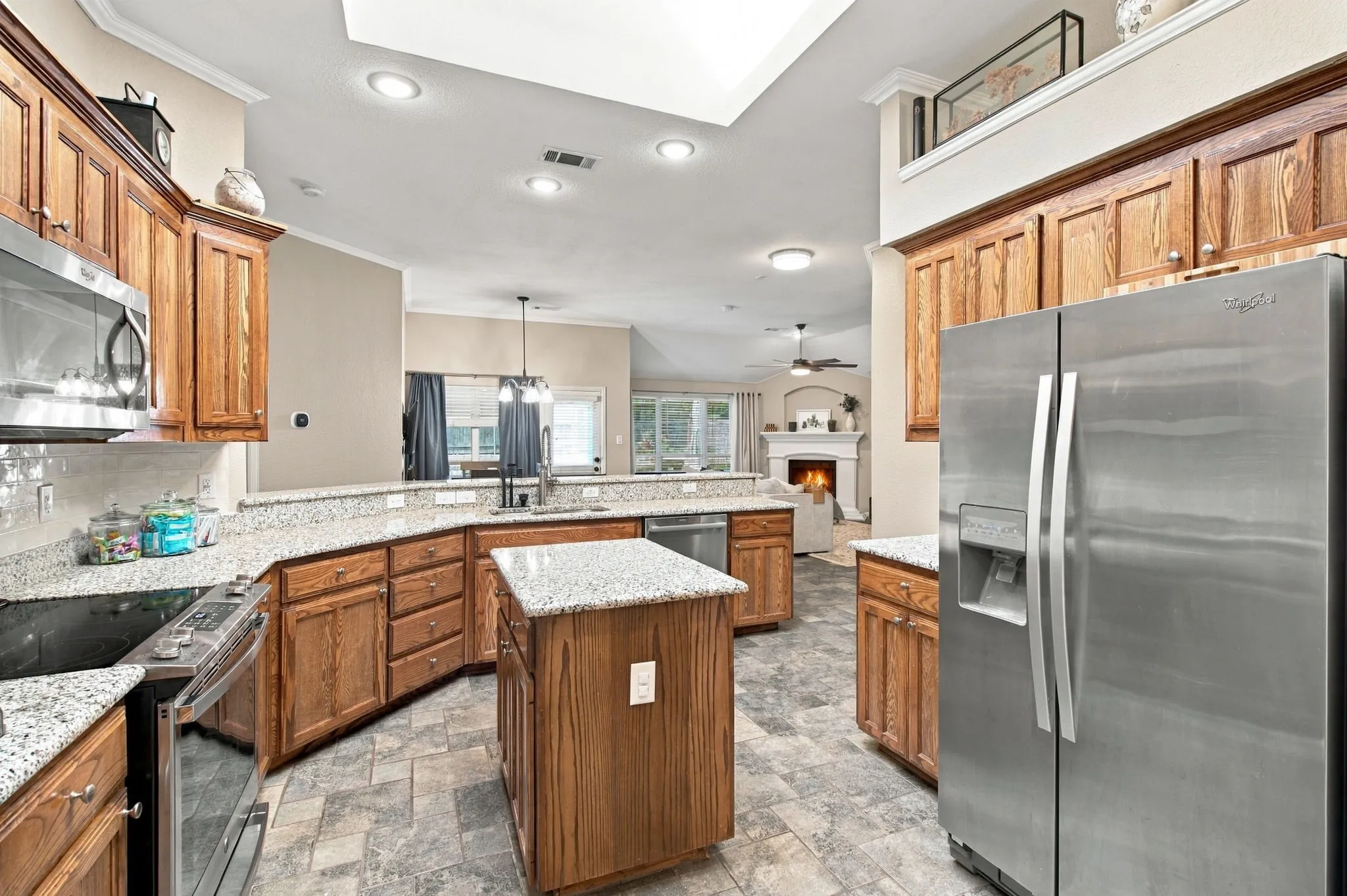 Kitchen featuring wood cabinetry, granite countertops, stainless steel appliances, and a central island